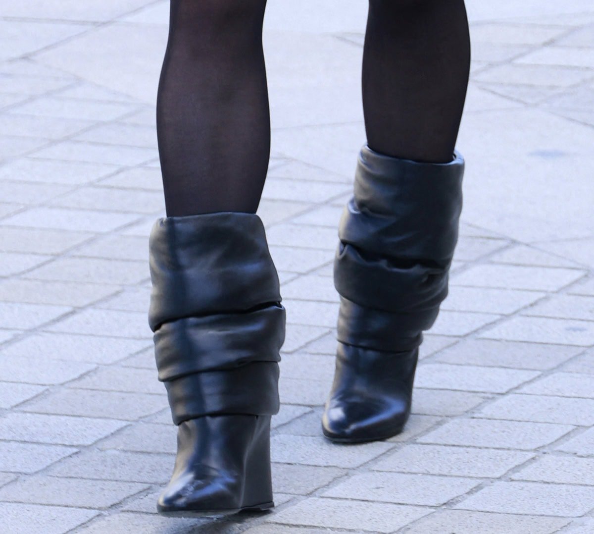 Sophie Turner pairs her theatrical ensemble with slouched boots featuring thickly padded shafts, pointed toes, and wedge heels