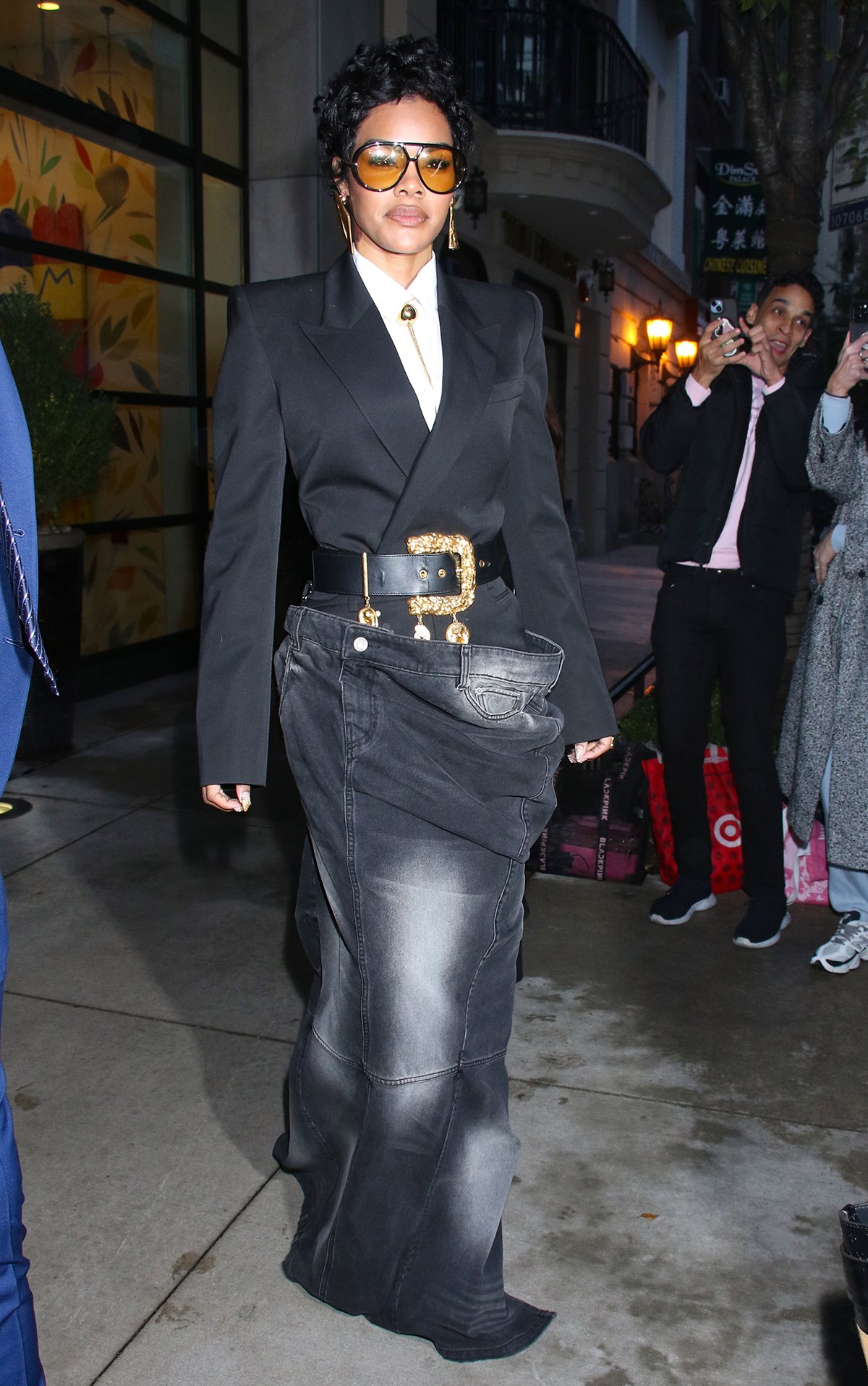 Teyana Taylor radiates power in a Juun.J blazer top, white shirt, gold chain tie, and oversized denim maxi skirt