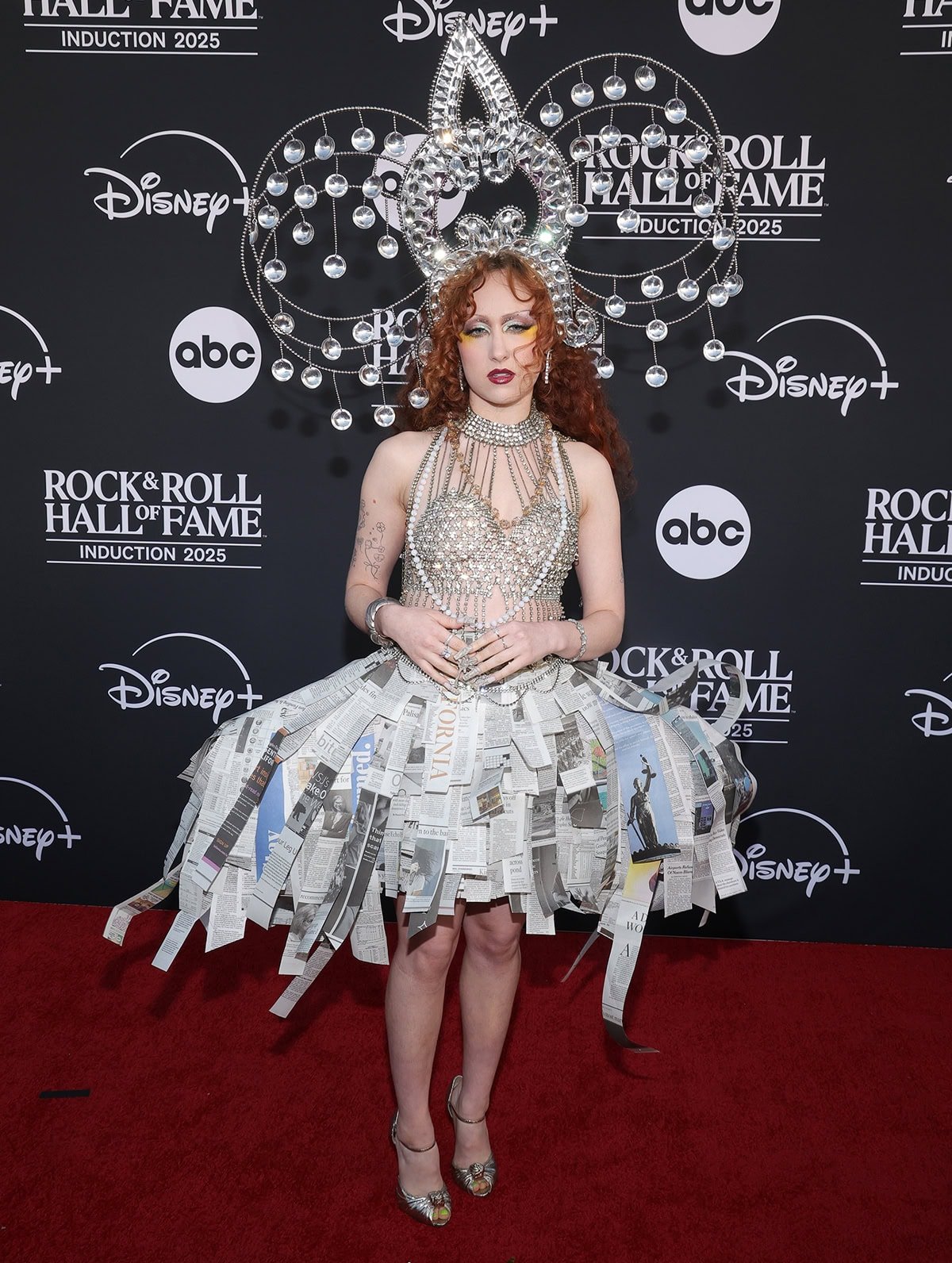 Chappell Roan channels Cyndi Lauper in the True Colors music video, wearing a crystal halter bustier top, a structured skirt made of shredded newspapers, and a headpiece featuring large circular frames and dangling orbs