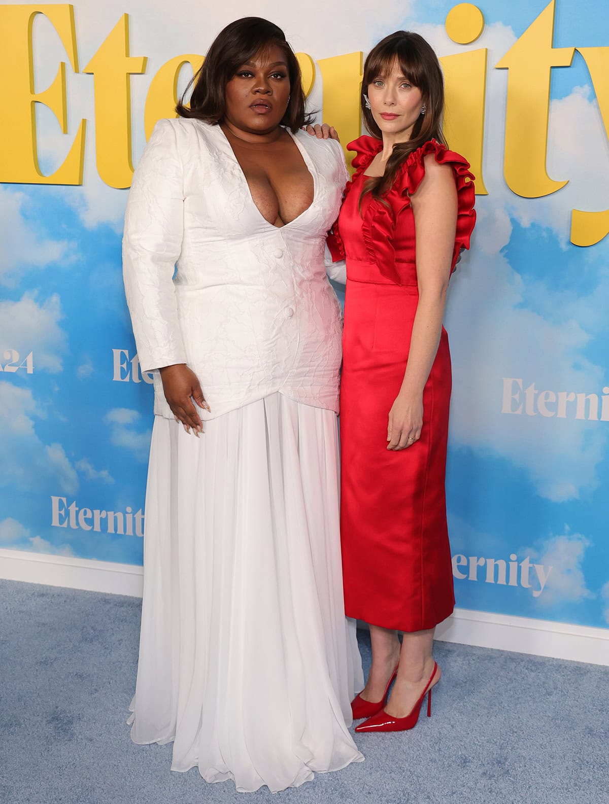 Da’Vine Joy Randolph and Elizabeth Olsen brought contrasting elegance to the Los Angeles premiere of A24’s Eternity at AMC Century City 15 on November 5, 2025 — Randolph radiant in a white Laith Maalouf gown and Olsen striking in a red Miu Miu dress paired with matching Le Silla pumps