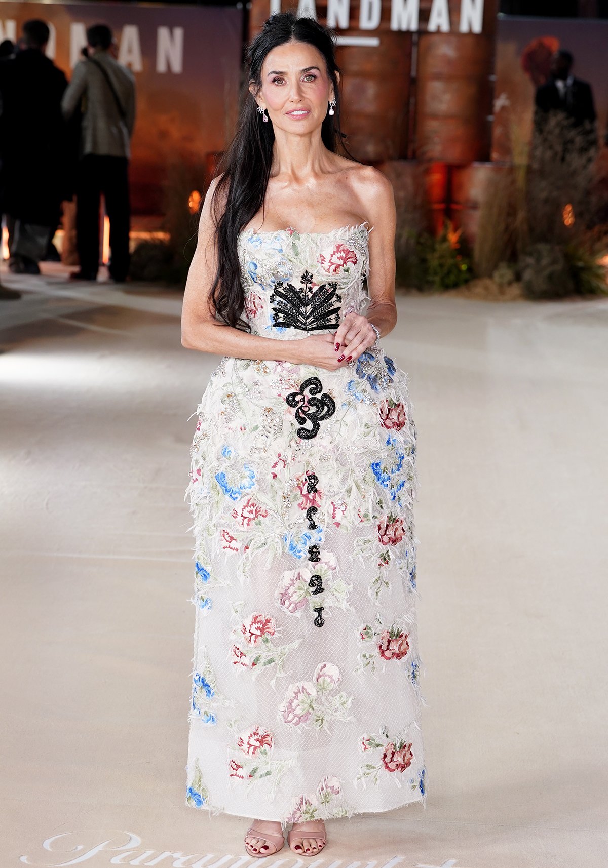 Demi Moore wows in a romantic white sheer netted dress by Erdem featuring frayed trims, colorful florals, and clusters of crystals at the UK premiere of Landman at Cineworld Leicester Square