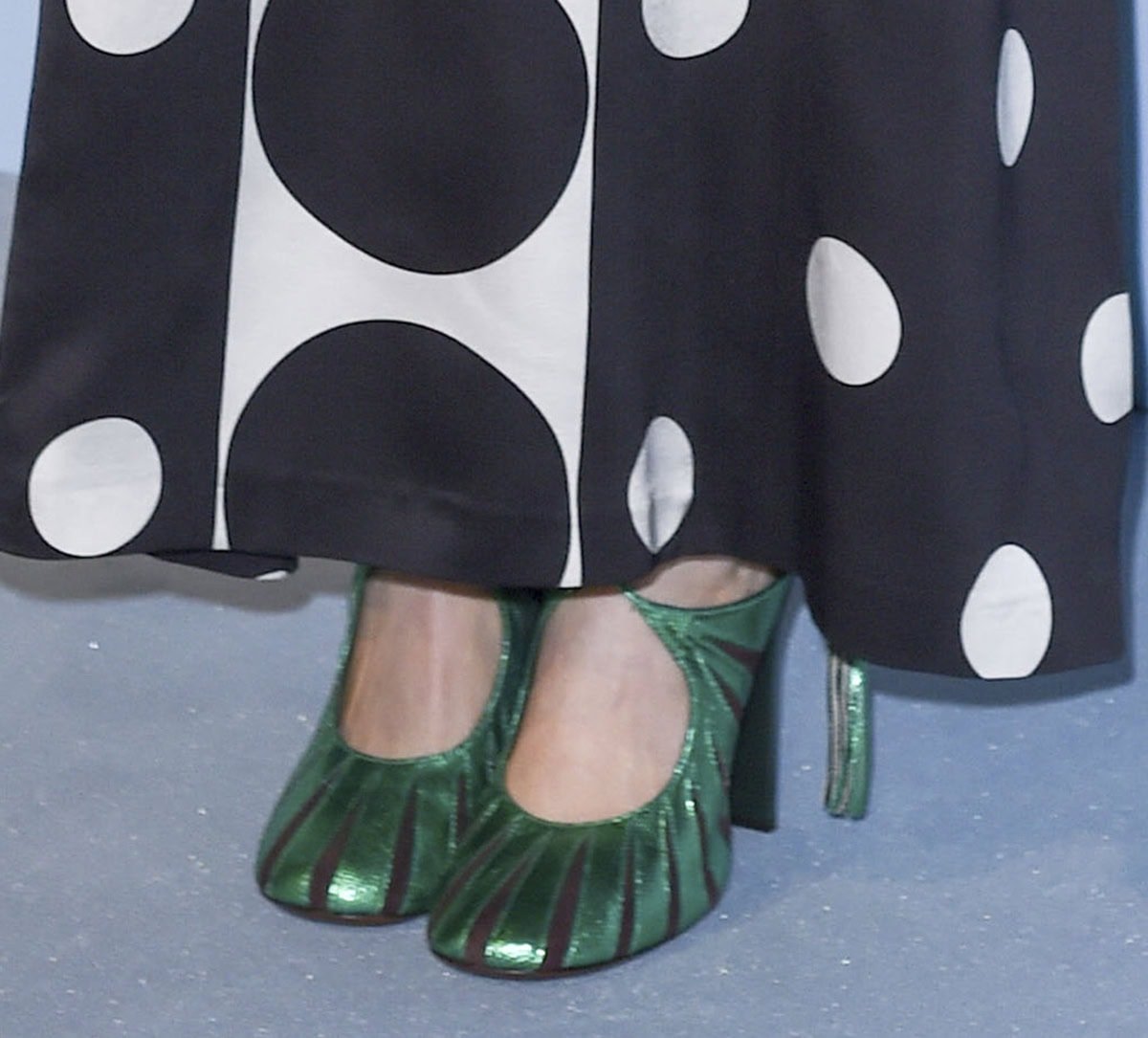 Elizabeth Olsen adds a pop of color to her modern black-and-white dress by wearing a pair of metallic green Dries Van Noten pumps with crisscross lace-up ties, black cutouts, and high heels