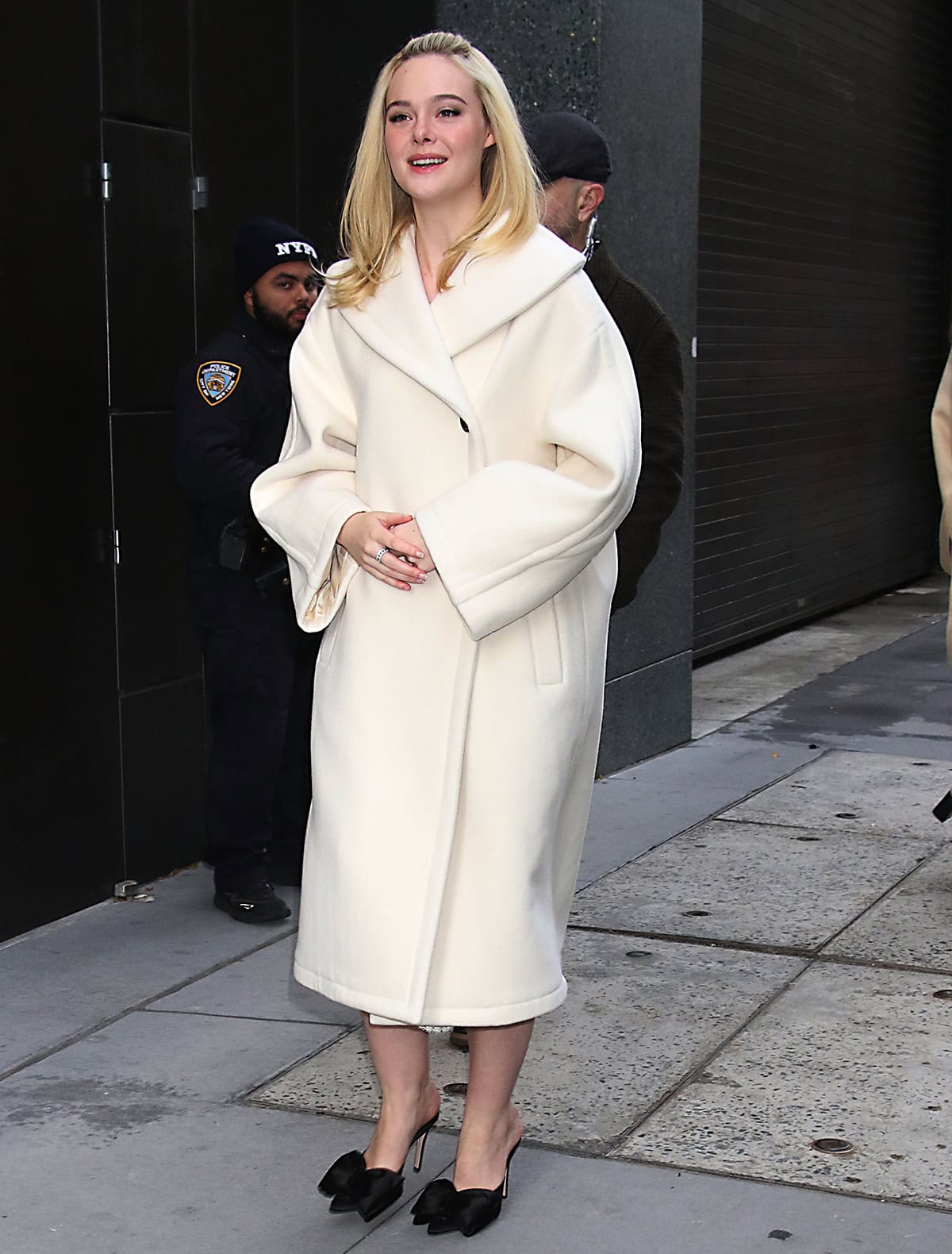 Elle Fanning arrives at the Good Morning America studios in a cream The Row coat, pairing the oversized silhouette with black satin Valentino bow mules in New York City on November 7, 2025