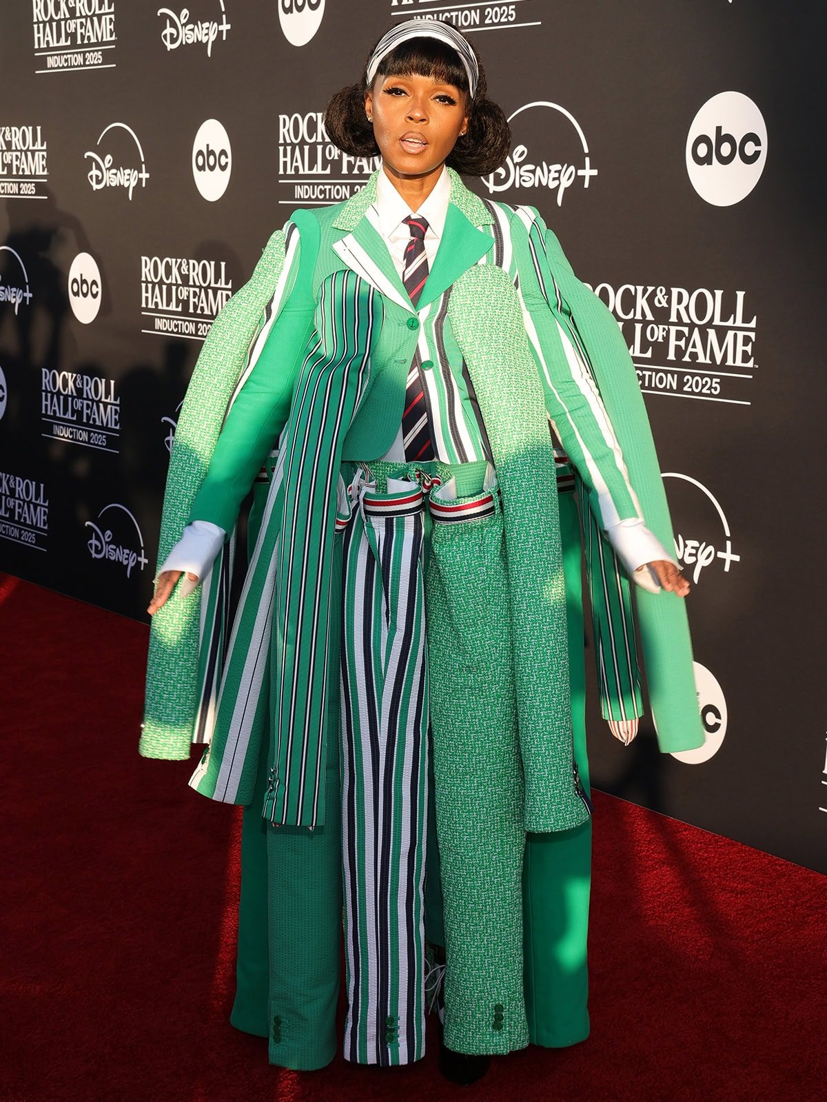 Janelle Monáe embraces deconstructed tailoring in a green Thom Browne Spring 2026 suit featuring a blazer and matching pants with extra sleeves and legs made of different fabrics