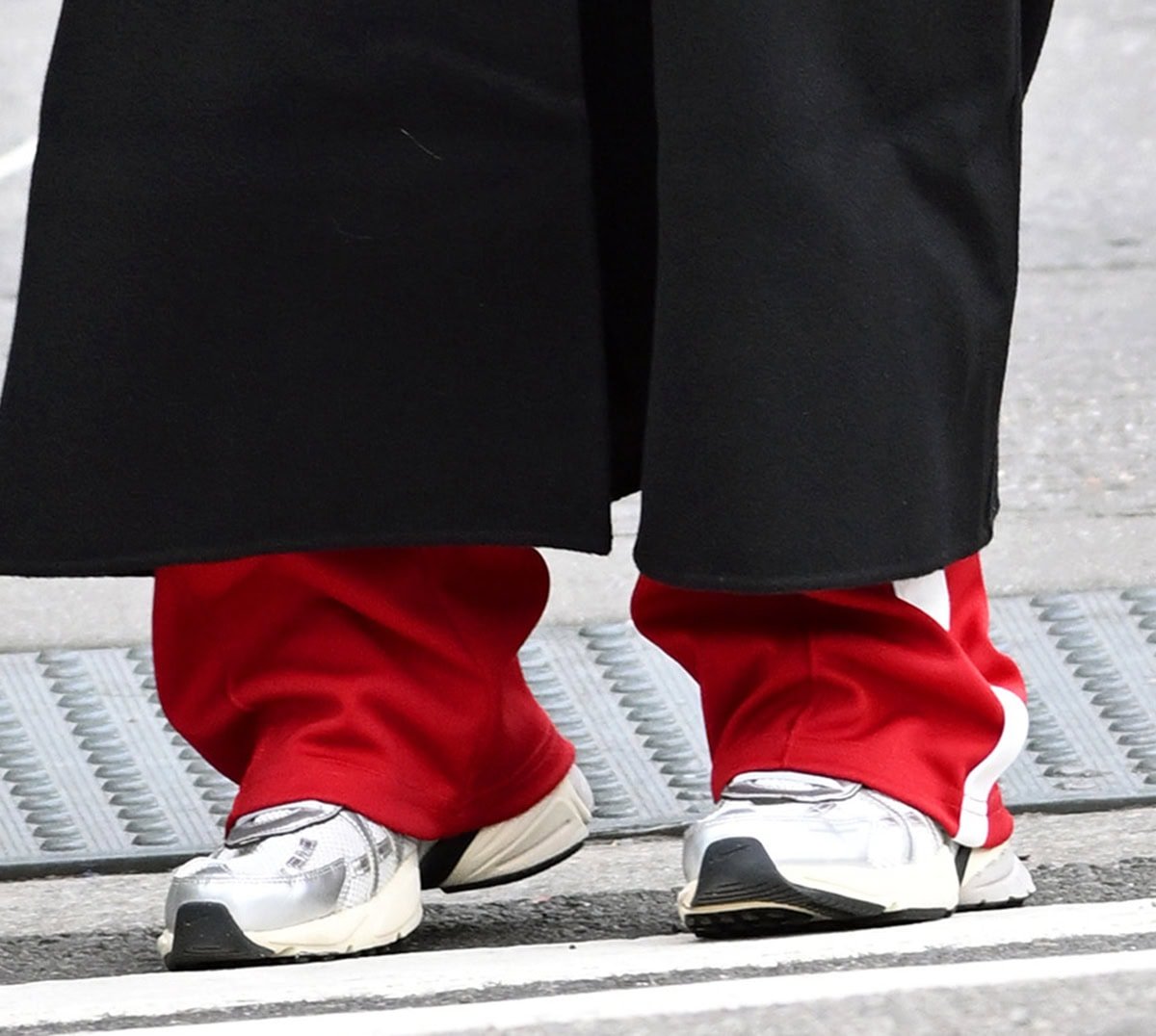 Close-up of Jennifer Lawrence wearing silver Nike V2K Run sneakers with red track pants and a black coat during a fall outing in New York City