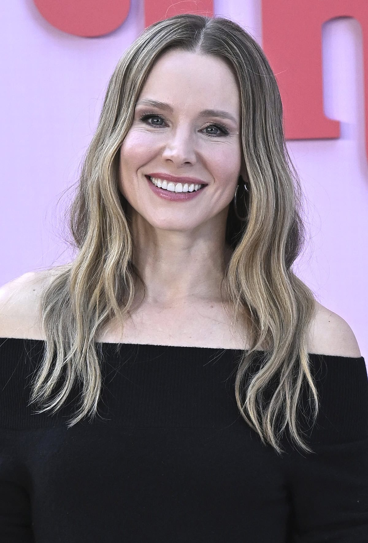 Kristen Bell highlights her features with soft pink makeup and accessorizes with just a pair of hoop earrings, hidden beneath her tousled waves