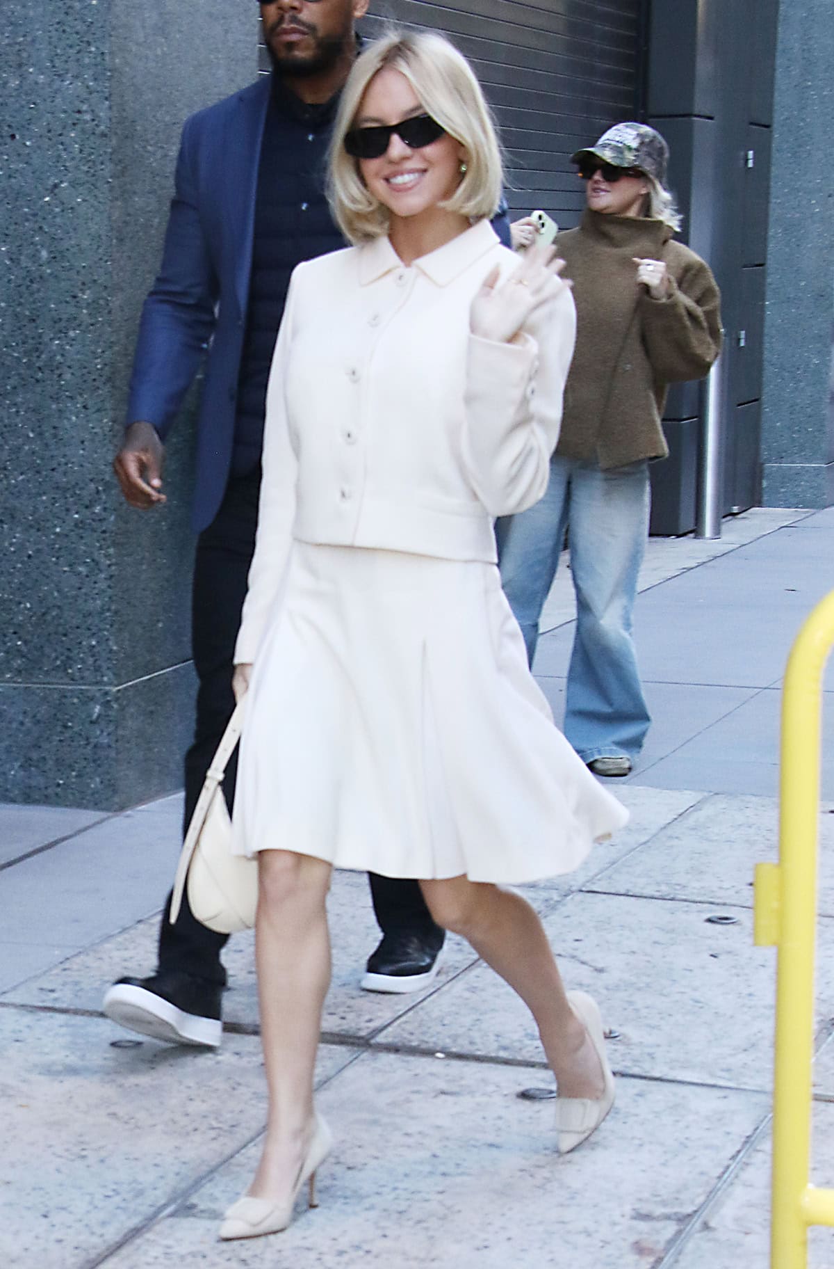 Sydney Sweeney looks modest and chic in a vintage Versace 1996 blazer top and a knee-length pleated skirt