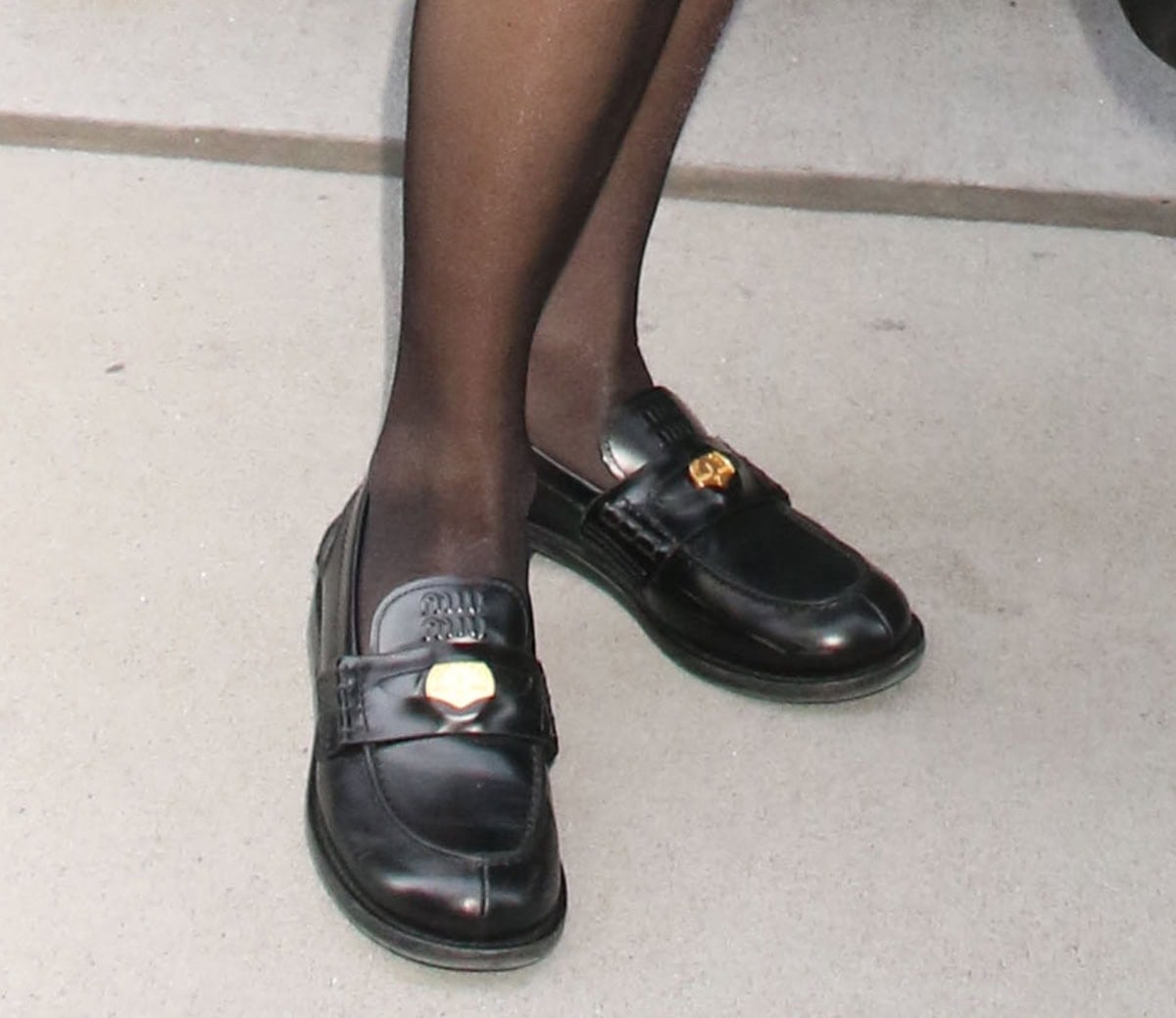 Amanda Seyfried completes her understated but chic winter look with black tights and Miu Miu penny loafers featuring a gold metal penny and a logo-embossed tongue