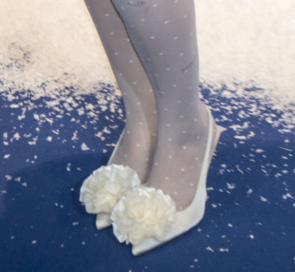 Anne-Marie embraces winter-white glamour in polka-dot stockings and white slingback pumps with an intricate 3D floral accent