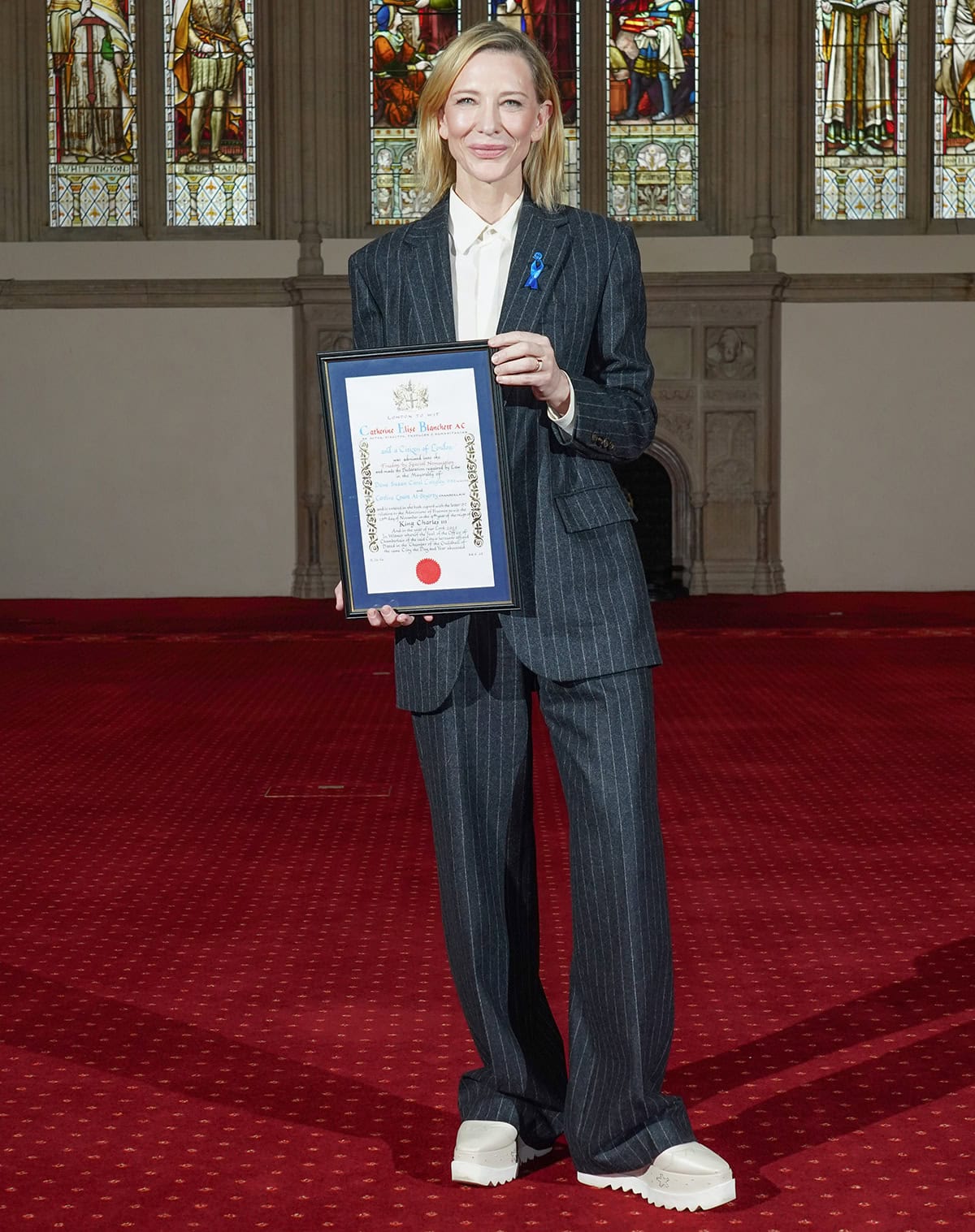 Cate Blanchett teams her casual but chic footwear with a tailored pinstriped suit featuring an oversized jacket, wide-legged pants, and a white shirt
