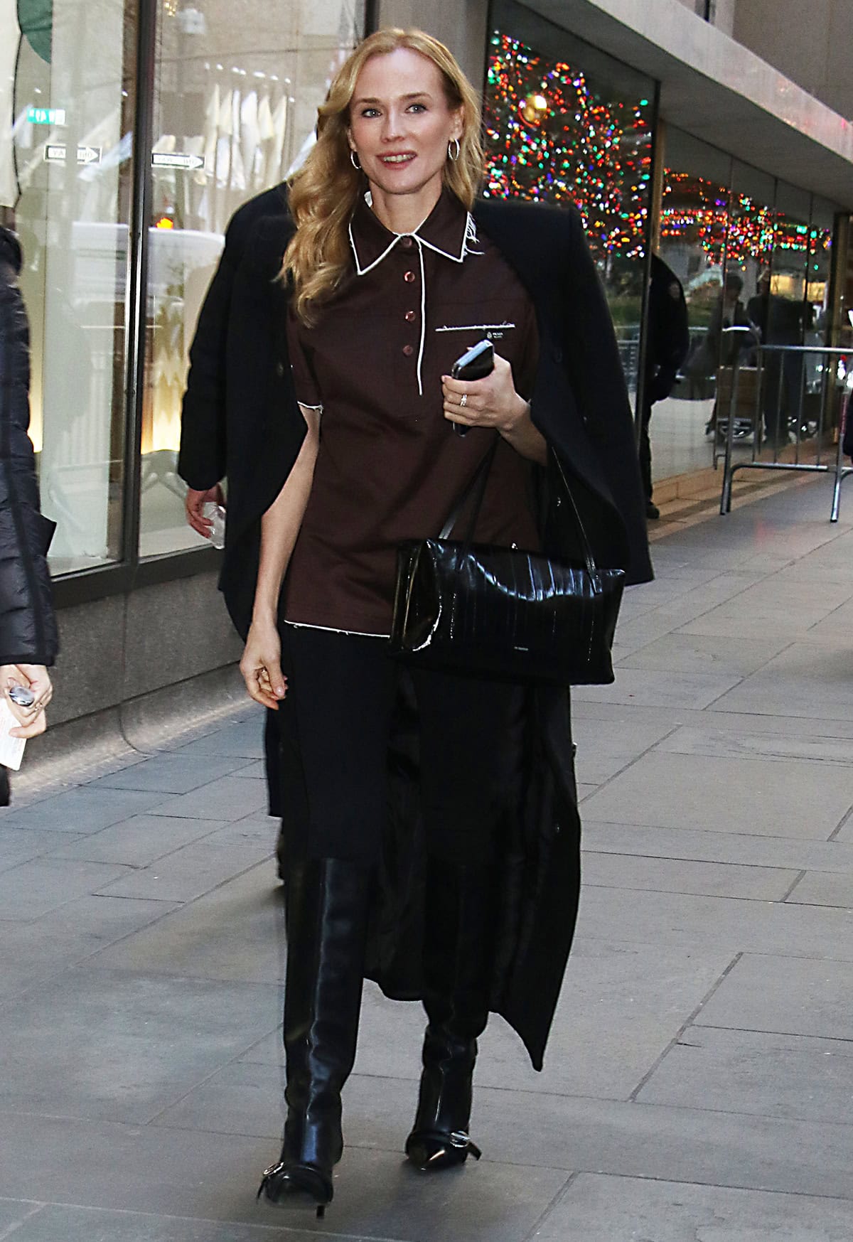 Diane Kruger pairs basic leggings with a simple brown lisle cotton Prada shirt featuring a shirt collar, contrasting white trims, and raw hems