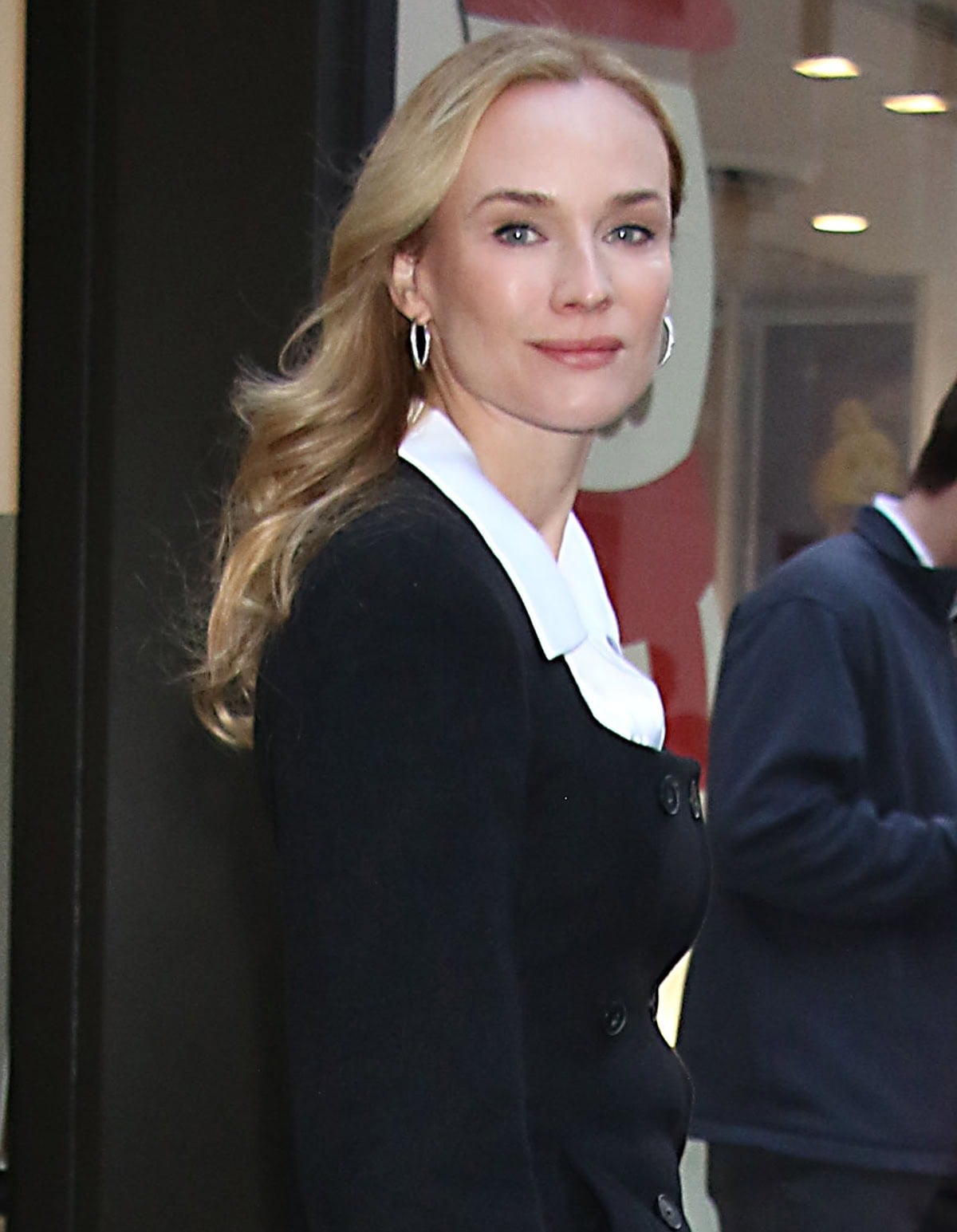 Diane Kruger elevates her casual ensemble with hoop earrings, wavy hairstyle, and soft pink makeup