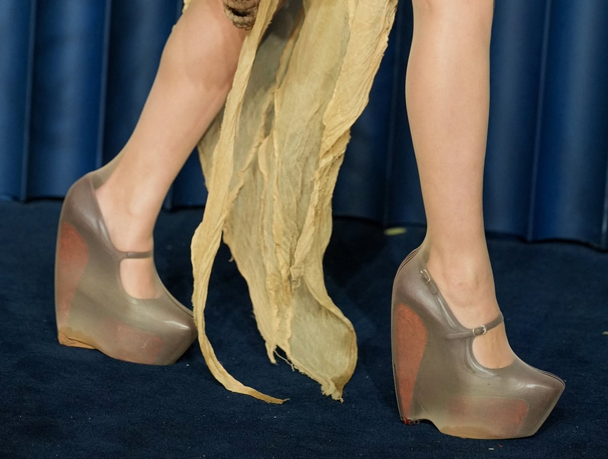 FKA Twigs slips into a pair of Balenciaga platform shoes featuring heels with polished wood inserts, square toes, and slim buckled straps