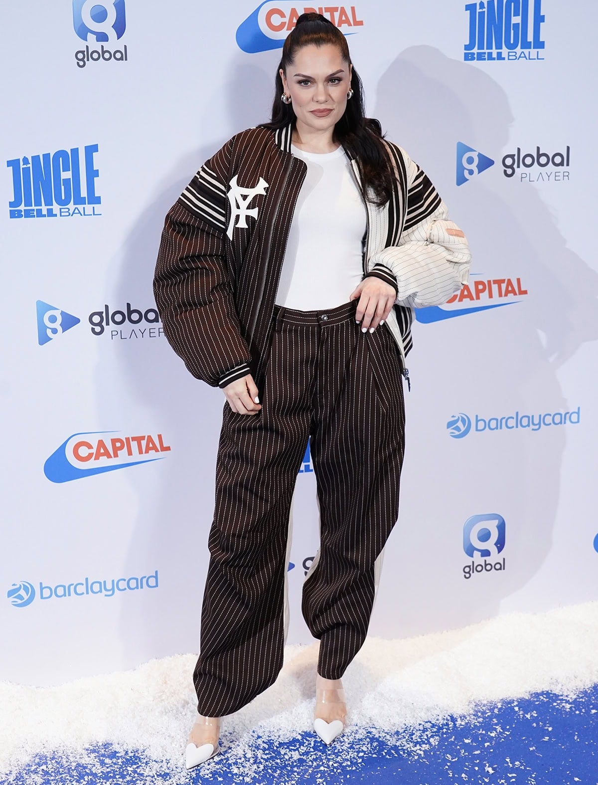 Jessie J pairs her feminine pumps with a brown-and-white striped bomber jacket, a white tee, and matching colorblocked striped pants by streetwear label PDF