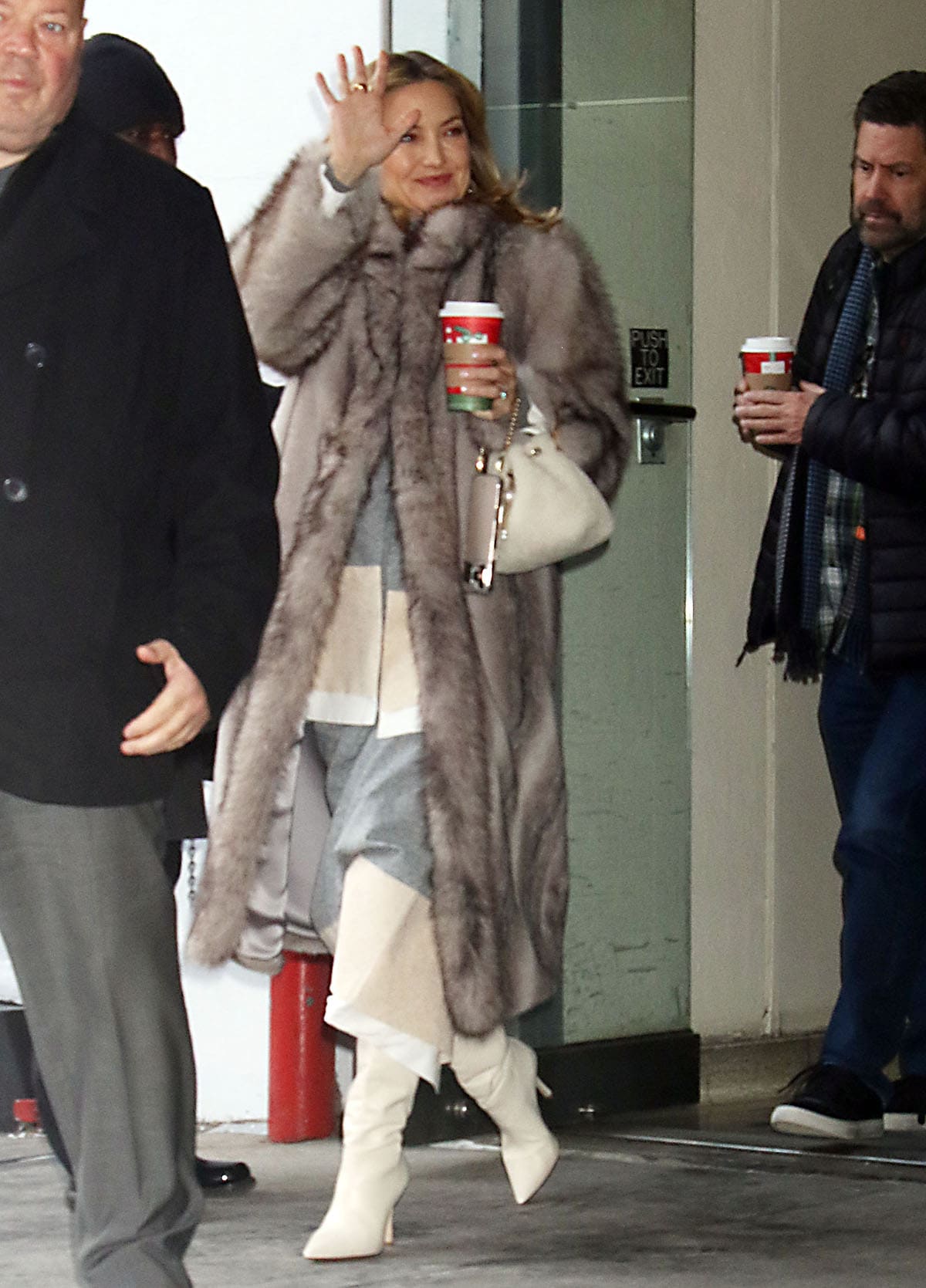 Kate Hudson lightens her winter look with slouchy white boots, revealing a gray-and-cream striped dress beneath her Ducie coat and finishing with an off-white Jimmy Choo “Bon Bon” bag