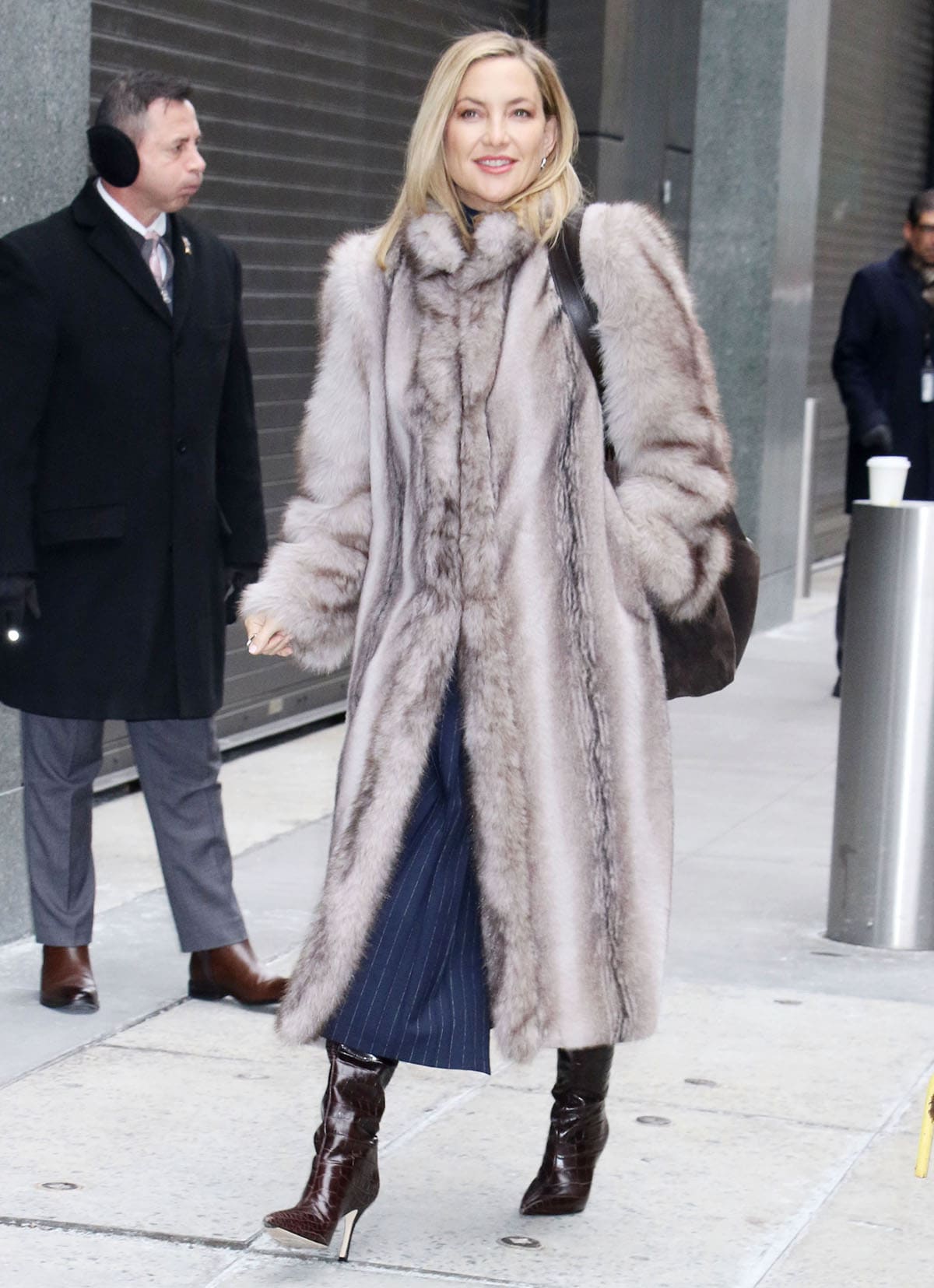 Kate Hudson brings modern edge to winter dressing, pairing croc-embossed stiletto boots with her plush Ducie coat layered over a navy pinstriped dress