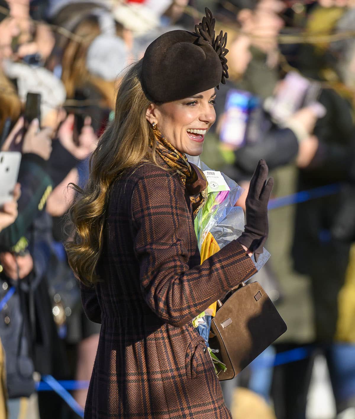 Kate Middleton pairs her checkered ensemble with a brown Cornelia James “Imogen” merino wool gloves, a mocha suede DeMellier “Small Hudson” bag, and a chocolate-brown Juliette Botterill hat