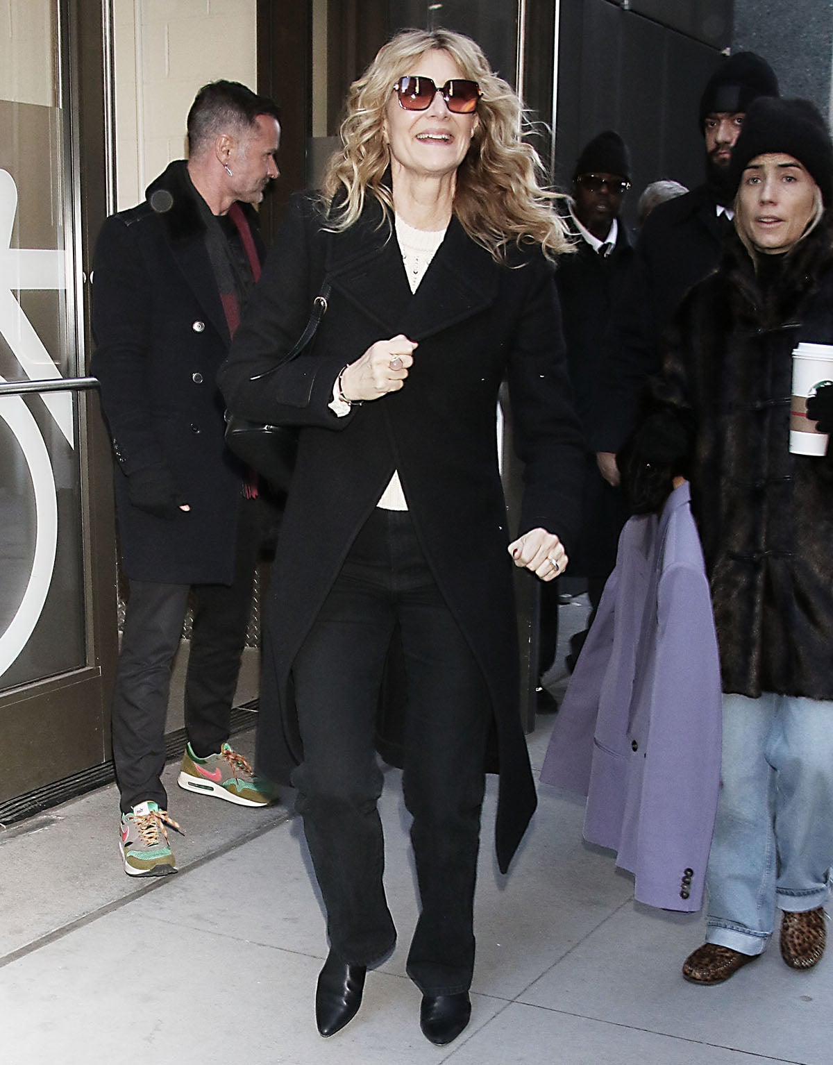 Laura Dern visits ABC Studios in black straight-leg jeans, a cream knit top with stud accents, and a black coat