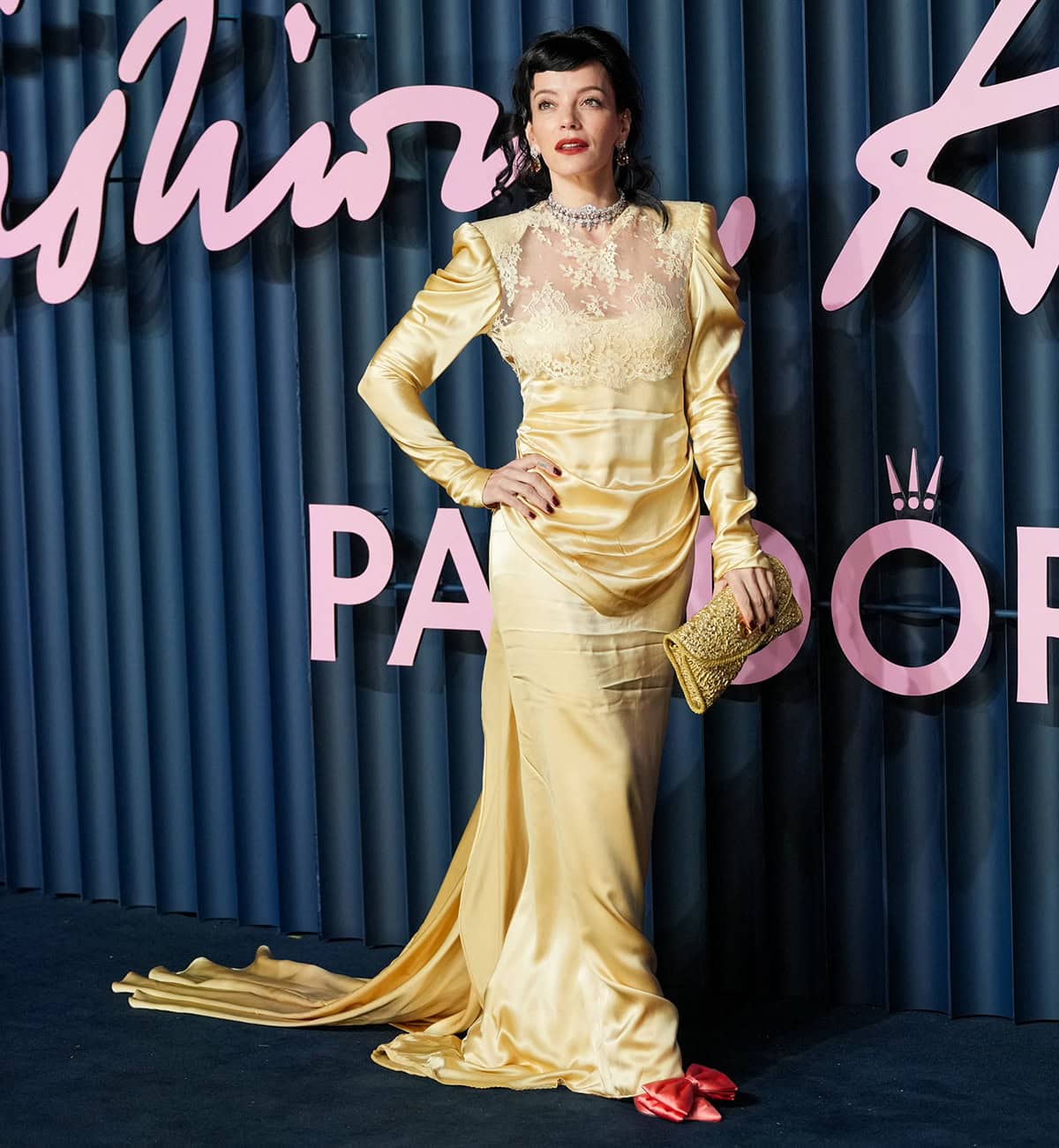 Lily Allen teams her pink shoes with a gold satin and lace Valentino gown, evoking Bridgerton-esque grandeur
