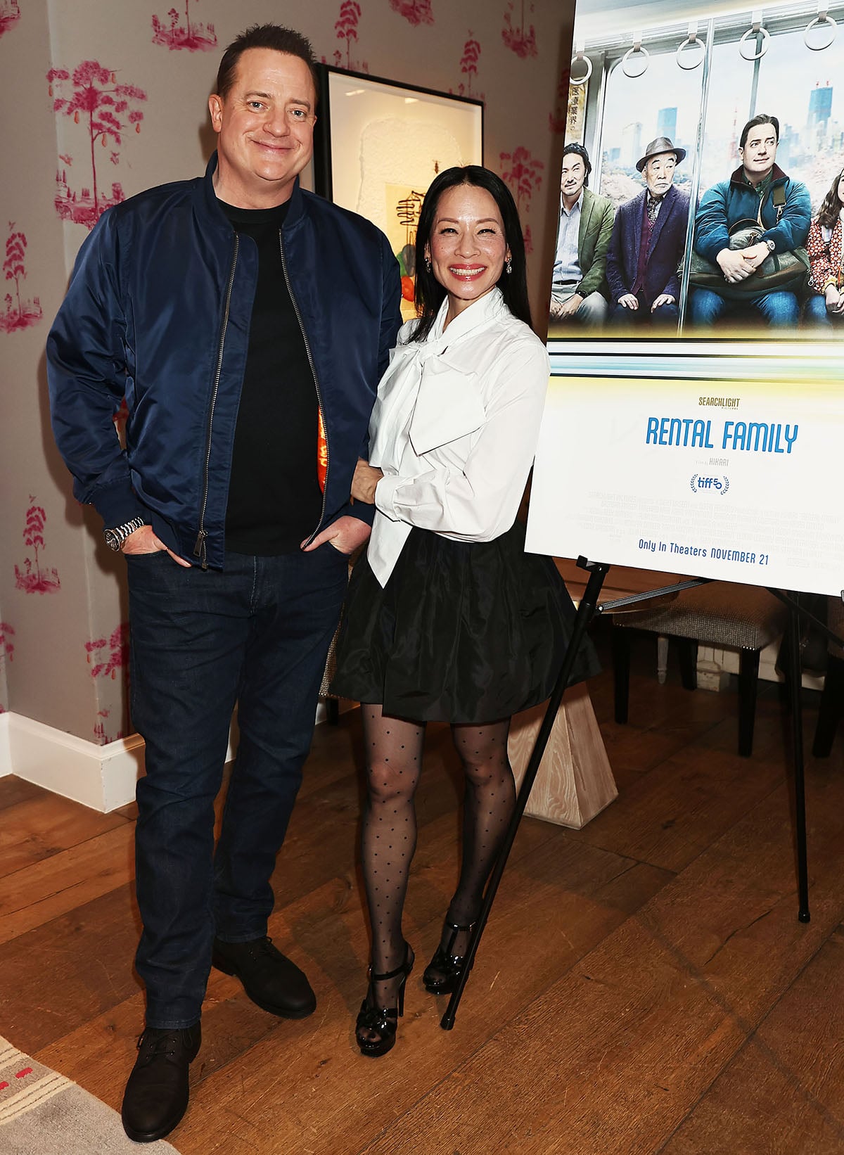 Brendan Fraser looks casual in jeans and a bomber jacket, while Lucy Liu embraces a sophisticated, flirty look in a white Patou shirt with an oversized bow tie and a black bubble mini skirt