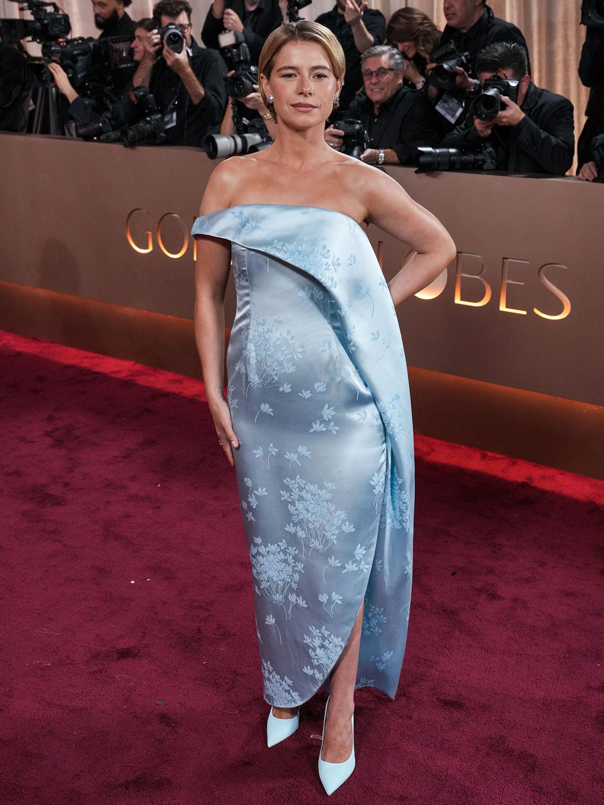 Jessie Buckley pairs her light blue Jimmy Choos with a blue satin Dior dress featuring a wrap-style silhouette and a floral motif