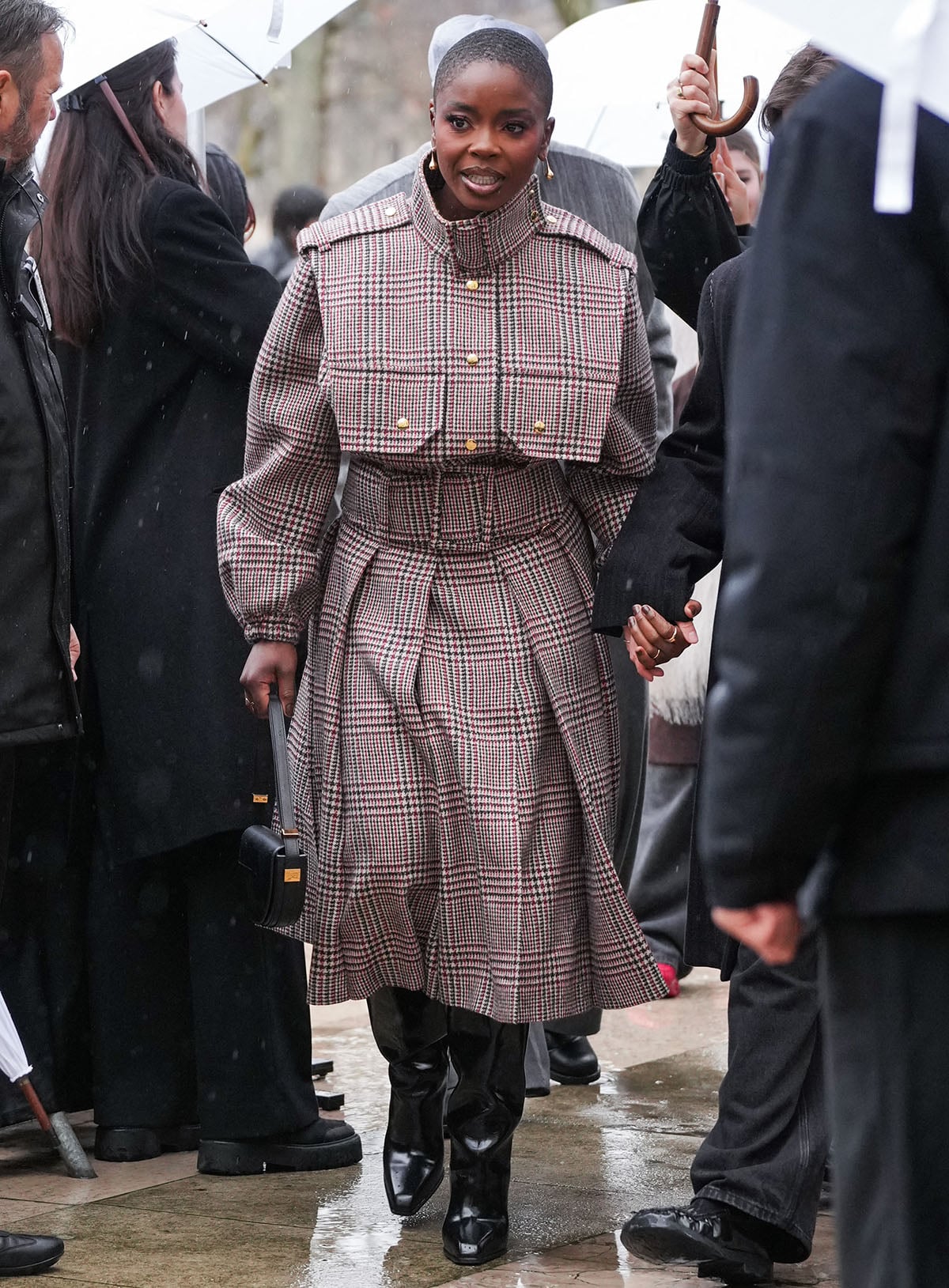Joy Sunday teams her boots with a cozy, structured plaid coat dress featuring a buckled stand-up collar, large chest pockets, and a wide buckled belt