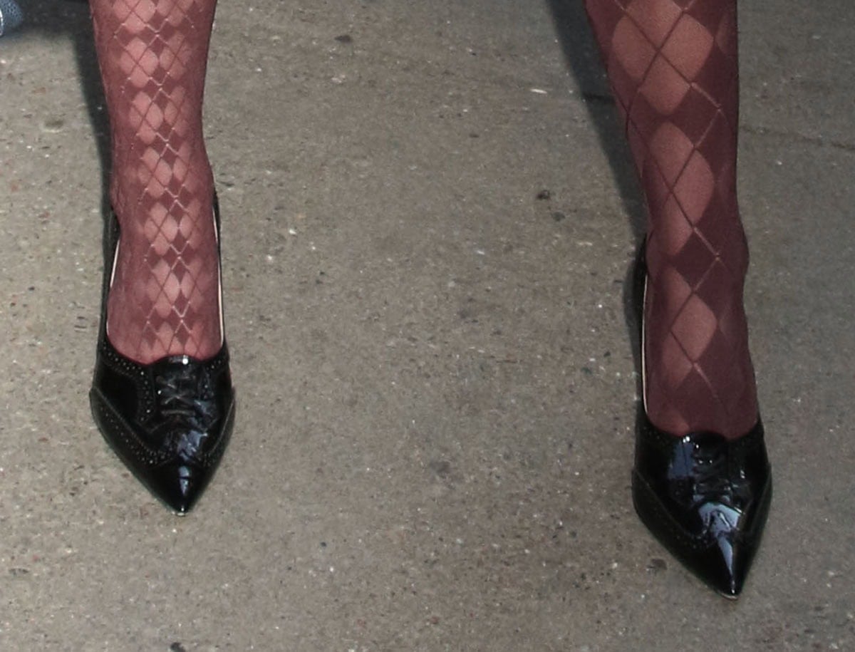 Kiernan Shipka completes her Thom Browne look with the burgundy “Funmix Argyle” sheer tights and a pair of black brogue-style pumps