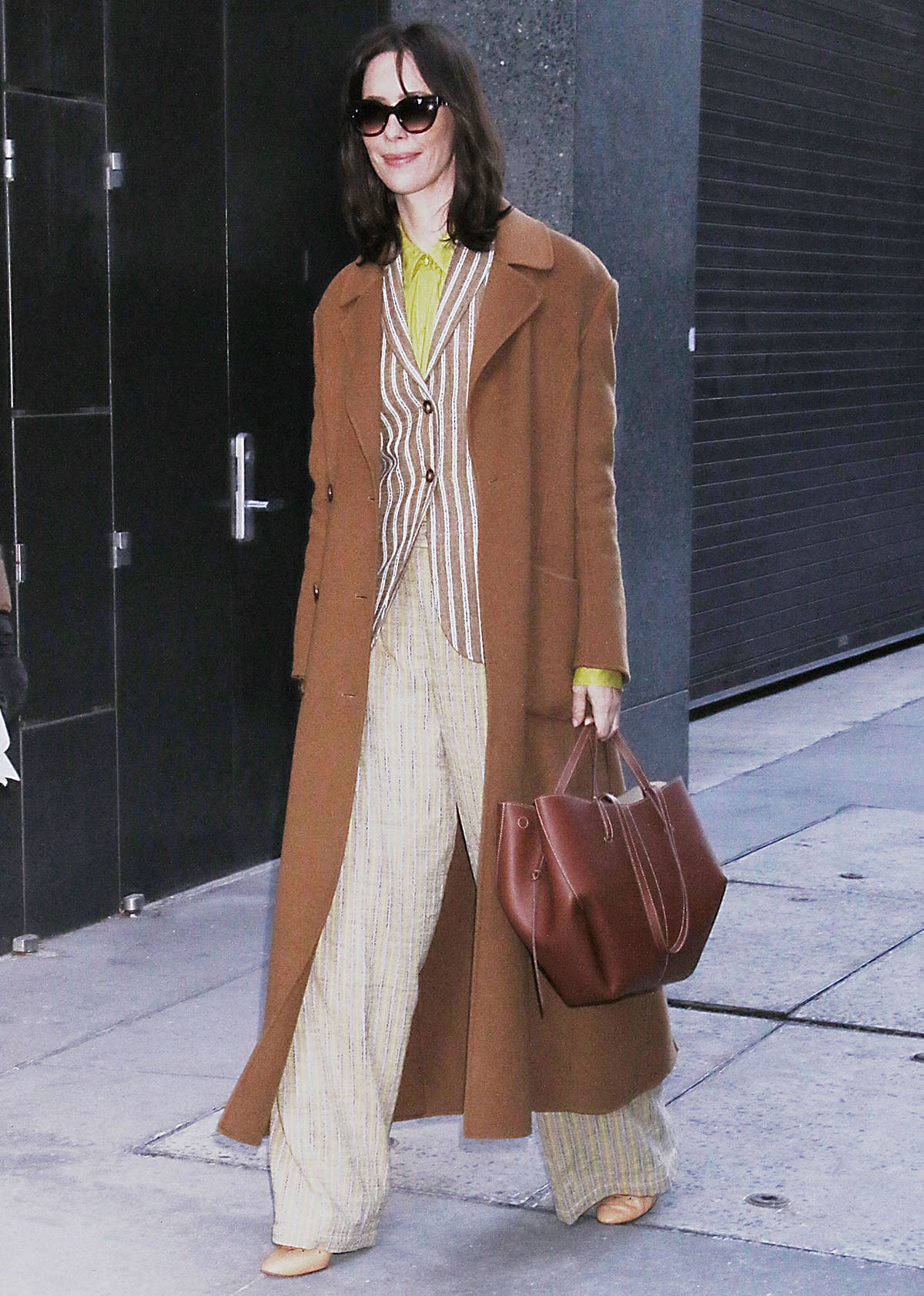 Rebecca Hall pairs her nude pumps with a bright, colorful ensemble featuring Ulla Johnson’s “Matteo” brown striped cotton-blend jacket, a chartreuse shirt, and the “Motherwell” striped pants