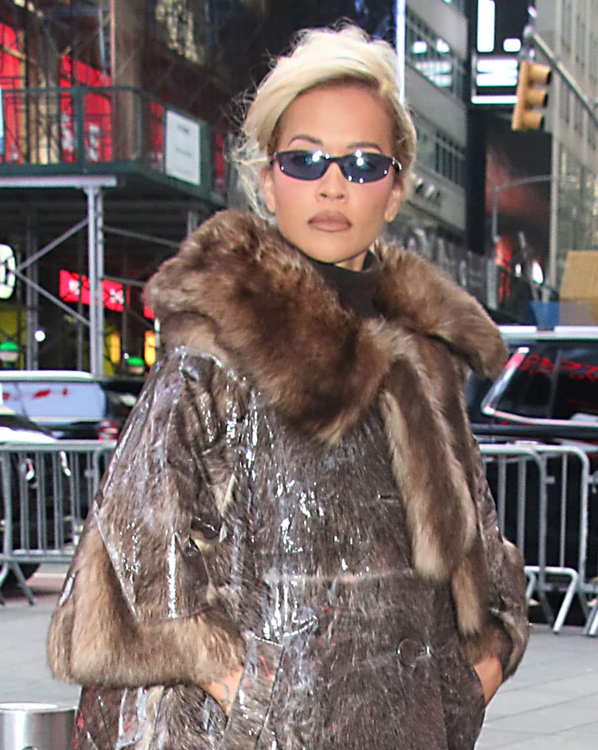 Rita Ora styles her blonde hair in a retro side-swept bun, wears neutral makeup, and hides her eyes behind Miu Miu sunglasses