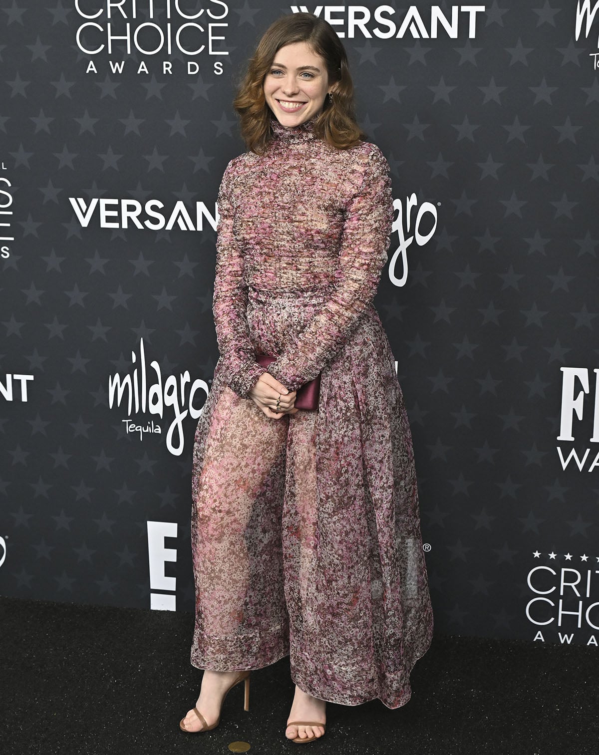 Sophia Lillis balances modesty with boldness in a rose-colored Giambattista Valli dress with a high neck, shirred long-sleeved bodice, and a see-through skirt