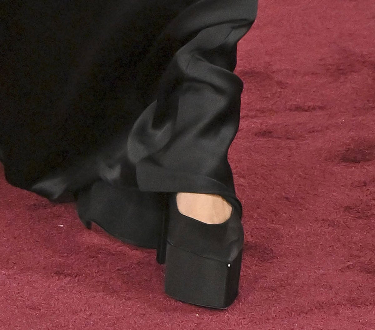 Teyana Taylor stands out in her towering black satin platform pumps with pointed toes, rounded vamps, and stiletto heels