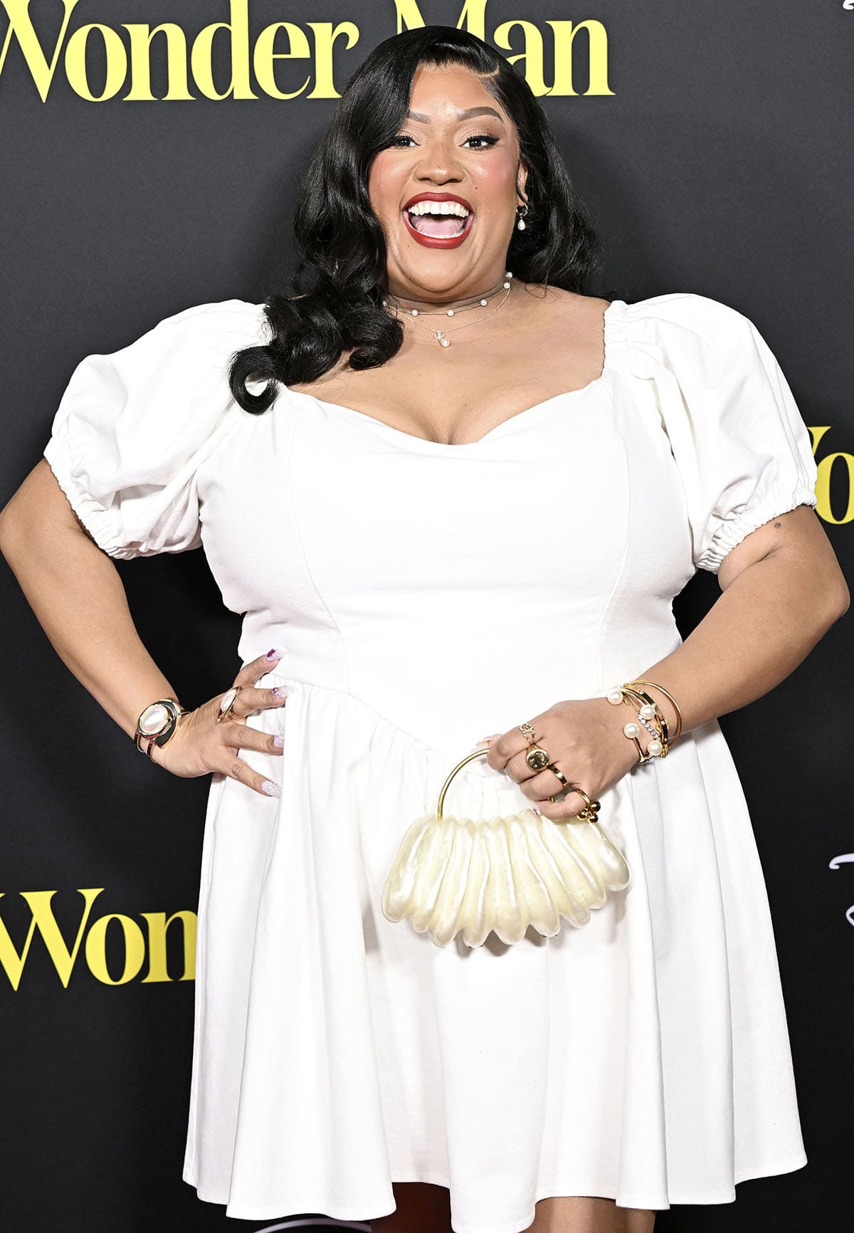 X Mayo pairs her understated white shoes with a white mini dress that features puff sleeves, a sweetheart neckline, and a ruffled mini skirt