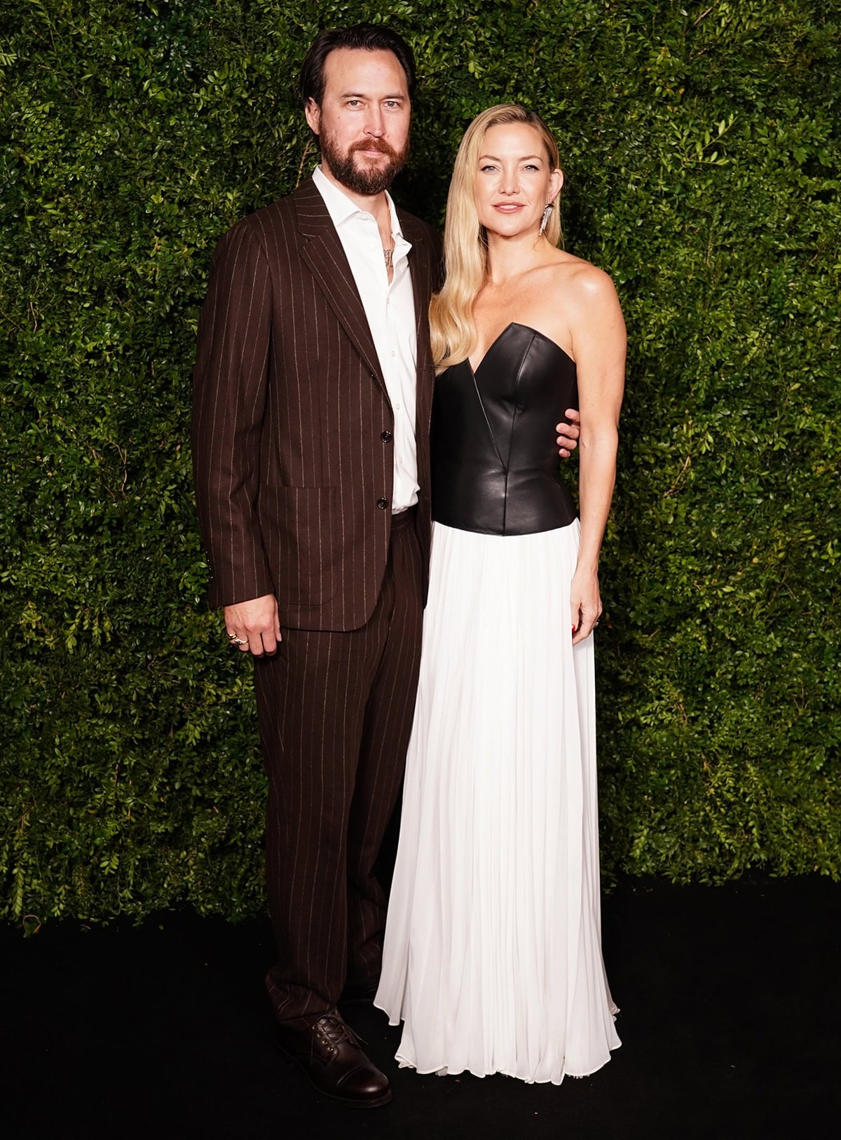 Kate Hudson, with fiancé Danny Fujikawa, stuns in an architectural black leather Ralph Lauren bustier top and an airy white maxi skirt