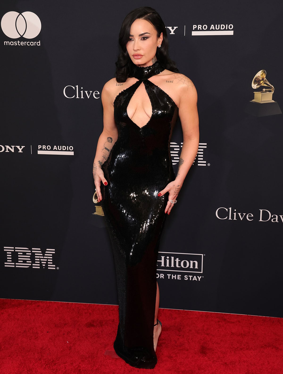 Demi Lovato pairs her minimalist black sandals with an equally shiny black sequin-embellished halter gown by Rodarte