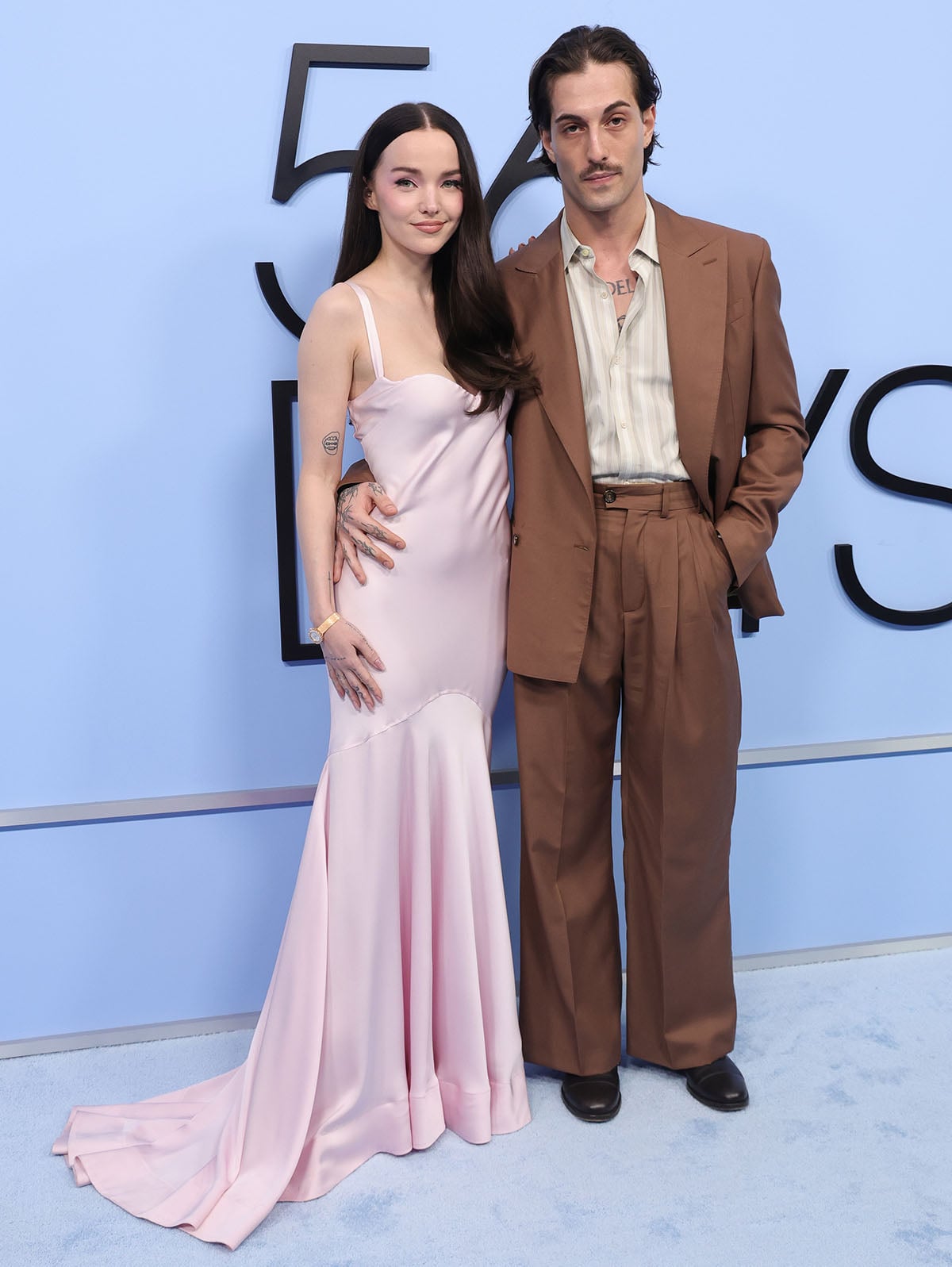 Dove Cameron elevates her blush pink slip gown with nude-pink platform heels as she arrives with fiancé, Damiano David, at the Los Angeles premiere of 56 Days