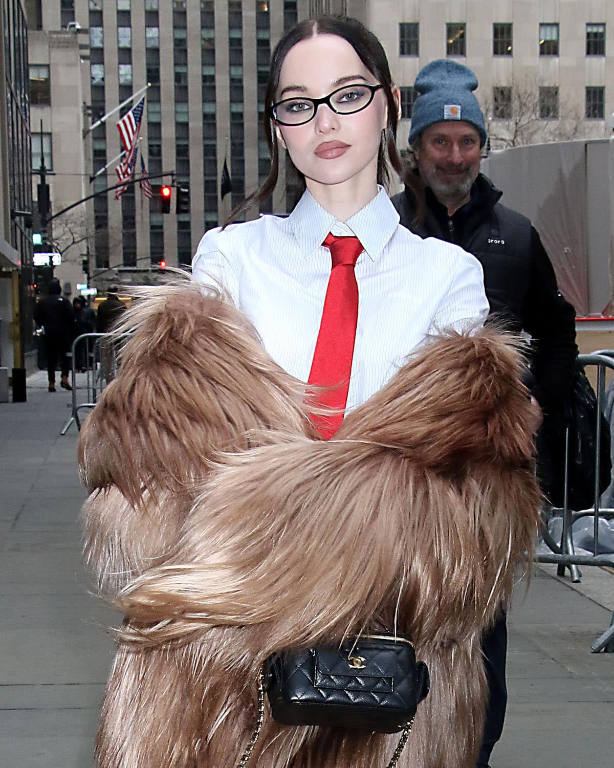 Dove Cameron styles her office siren look with a Chanel Mini Vanity bag and a pair of slim cat-eye glasses