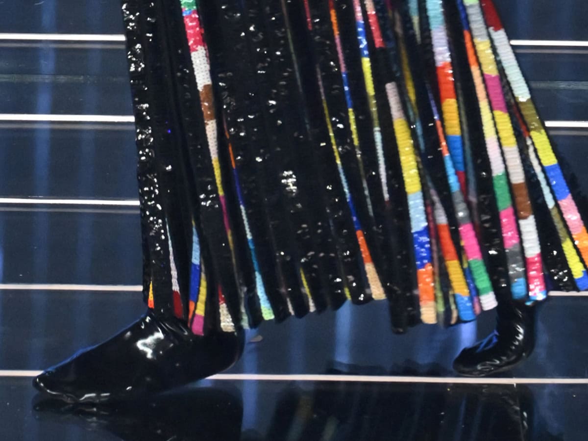 Irina Shayk wears a pair of glossy flat shoes, complementing her shimmering tasseled gown