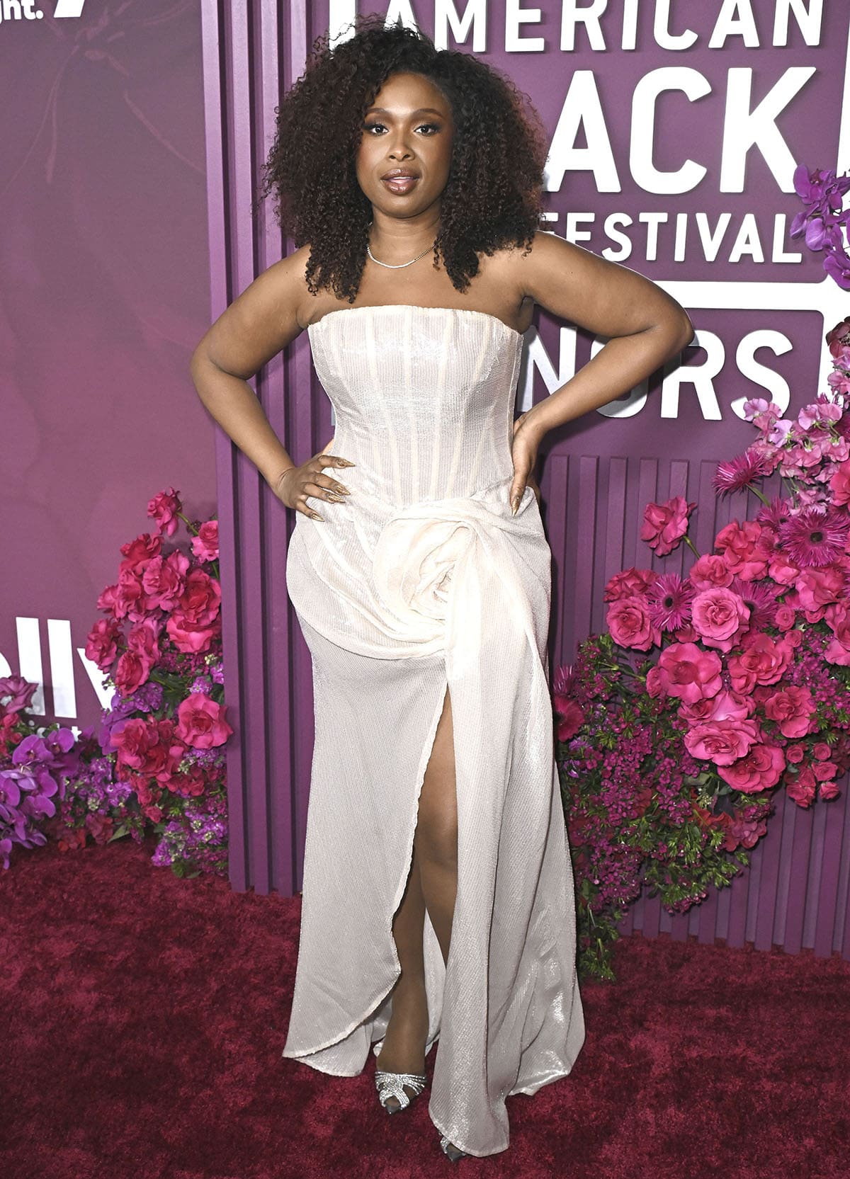 Jennifer Hudson looks radiant in a white sequin gown by Jean-Louis Sabaji, featuring a corset bodice and a wrap-style skirt with a dramatic 3D flower detail on the hip