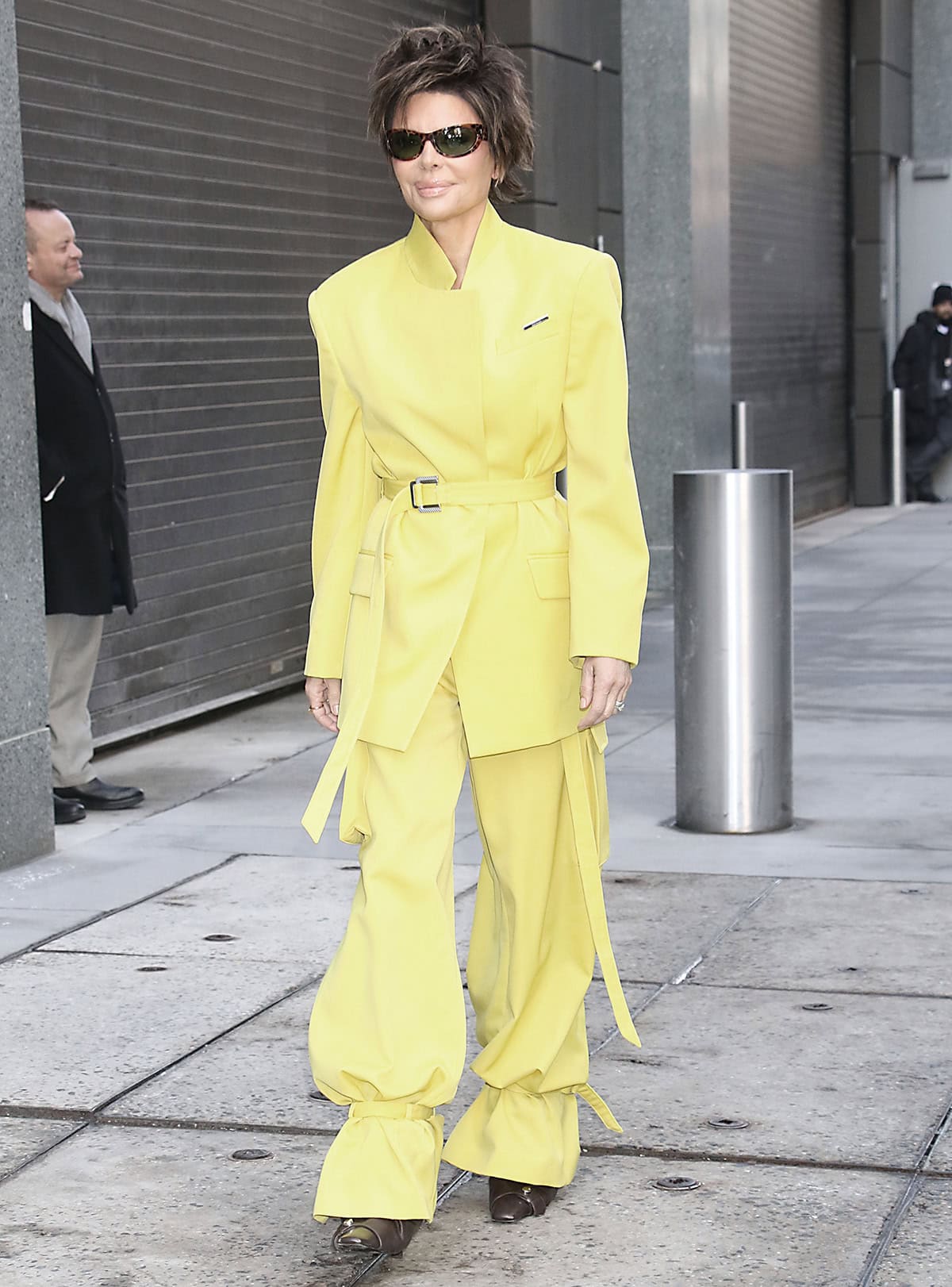 Lisa Rinna teams her brown boots with sunshine yellow The Attico jacket and matching cargo pants with cuffed ankles