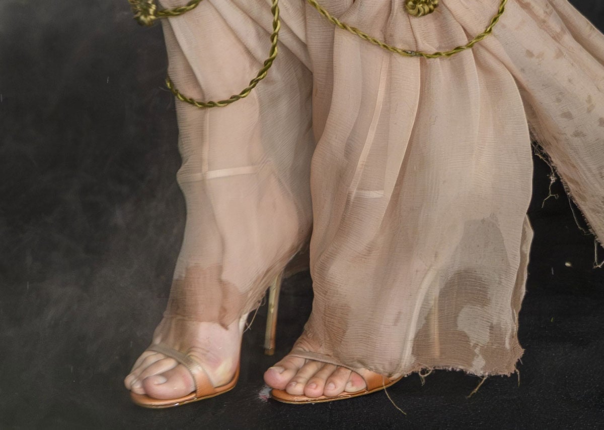 Margot Robbie slips into a pair of light beige open-toe sandals, custom-made for her by Manolo Blahnik, during the rainy premiere