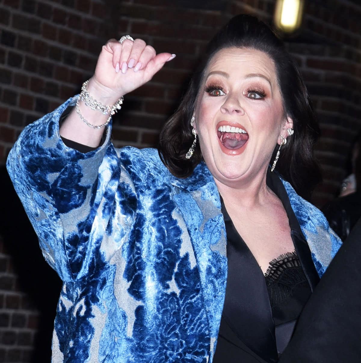 Melissa McCarthy pairs her striking outfit with diamond chandelier earrings, bracelets, and rings