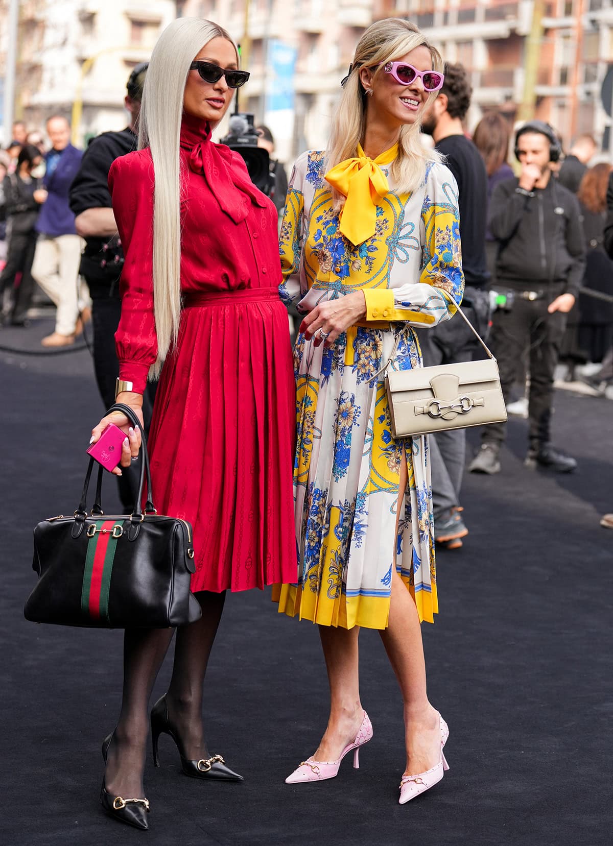 Paris Hilton pairs her Gucci pumps with a red logo jacquard Gucci dress featuring a high neck, a lavalliere ribbon, and a pleated skirt