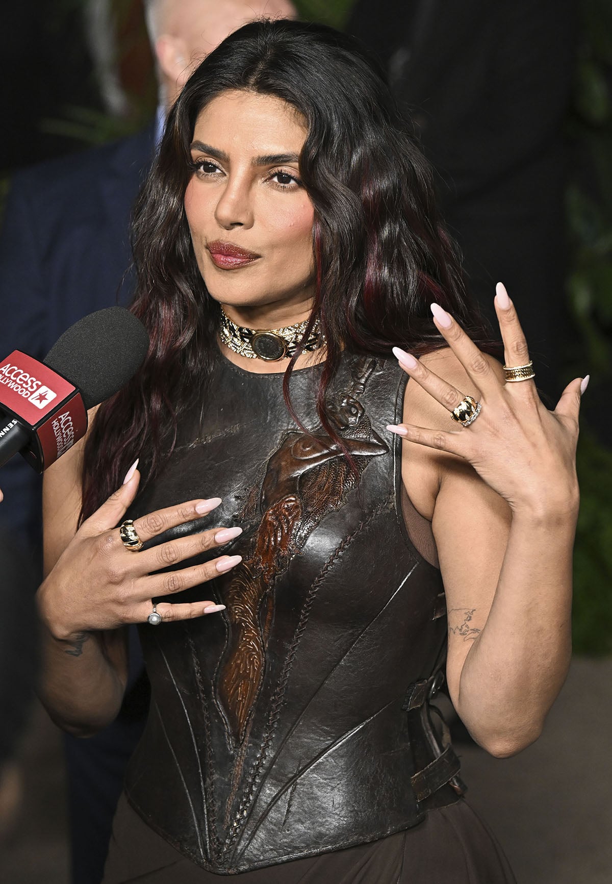 Priyanka Chopra styles her long hair in beachy waves, highlights her striking features with a rosy makeup palette, and accessorizes with jewelry by Bulgari