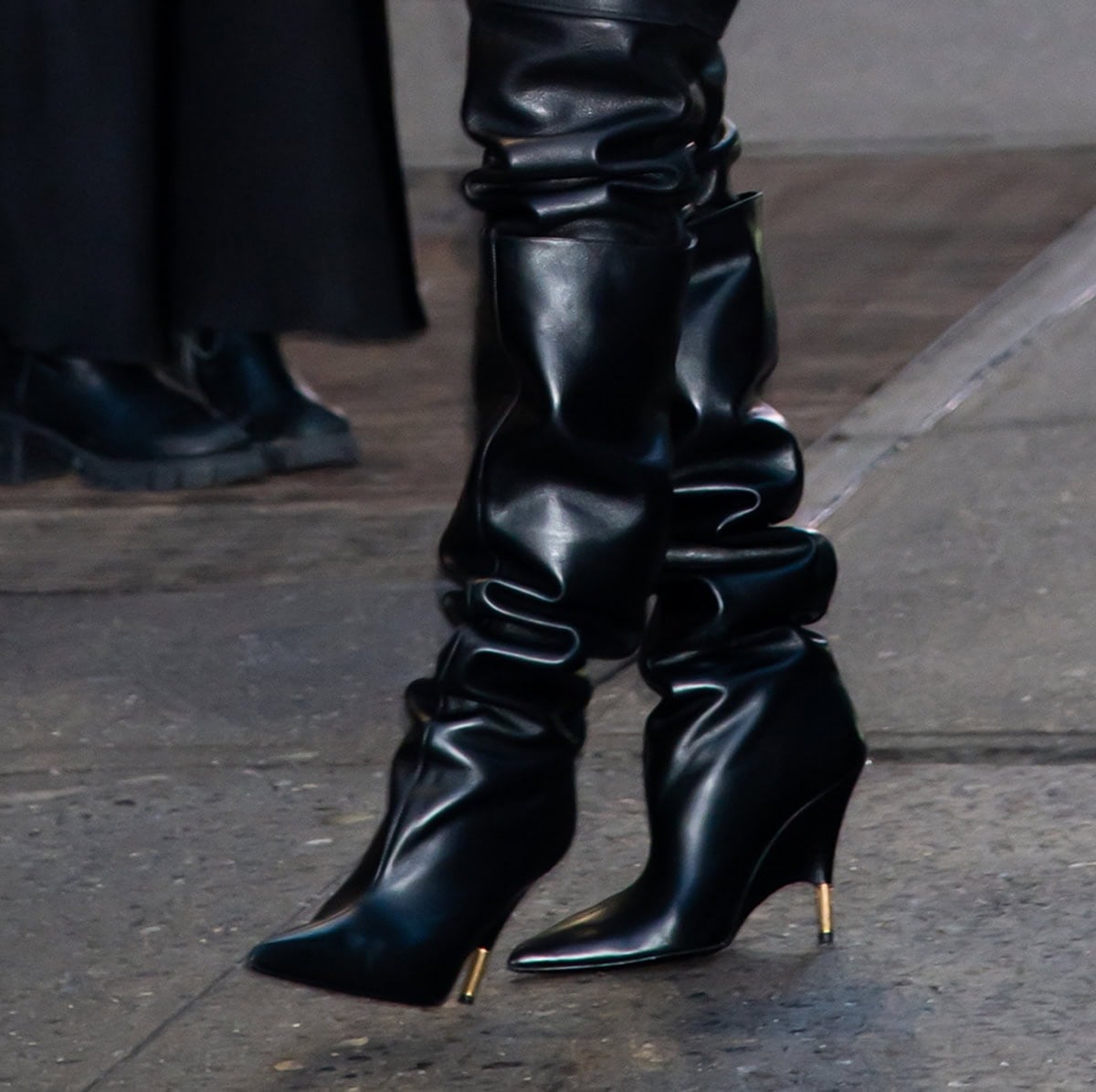 Teyana Taylor enhances her look's modern edge by slipping into the Khaite “Bella” boots with sculpturally wrapped wedge heels and Empire gold hardware tip