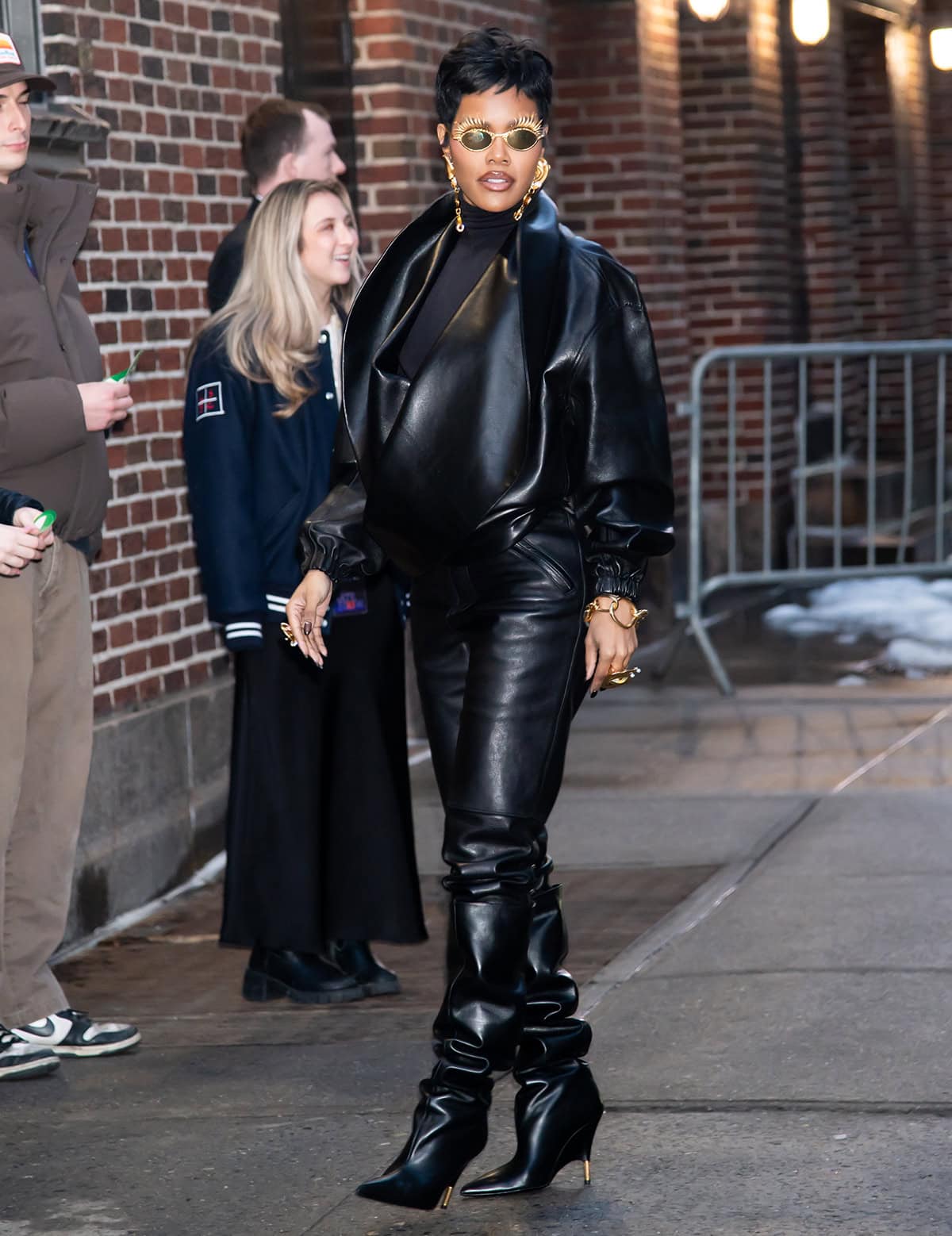 Teyana Taylor pairs her Khaite knee-high boots with black leather pants and an oversized black “Moon” bomber jacket by Phoebe Philo