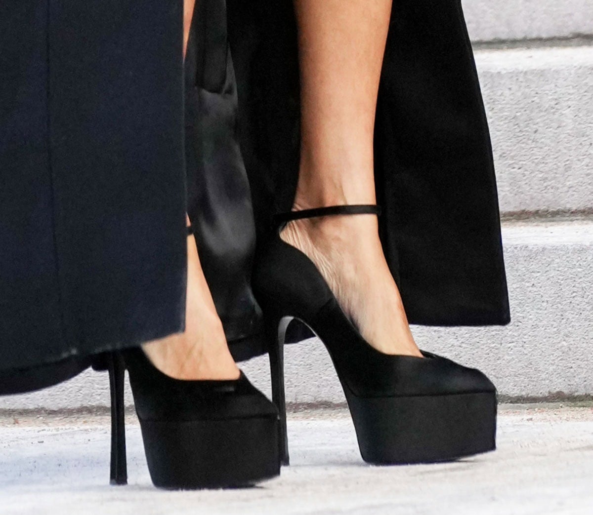 Teyana Taylor keeps her footwear simple, wearing a pair of black satin platform pumps with V-shaped vamps, pointed toes, and flared heels