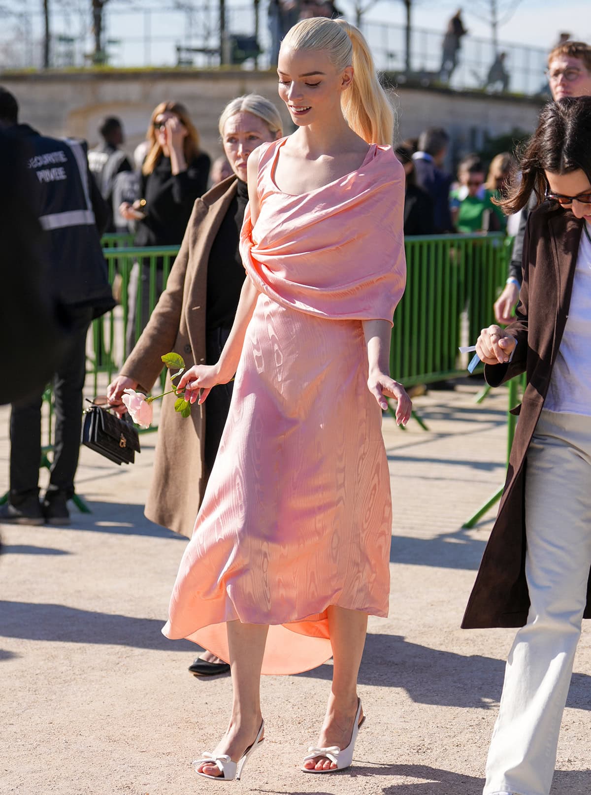 Anya Taylor-Joy pairs white Dior bow slingback heels with a peach moiré silk midi dress and matching shawl while arriving at the Dior Fall/Winter 2026–2027 show during Paris Fashion Week