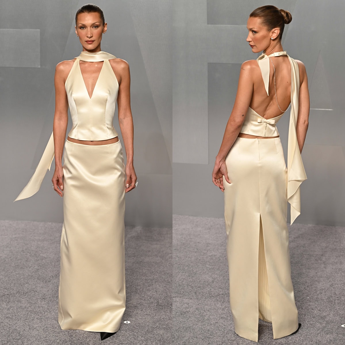 Bella Hadid pairs her black pumps with an ivory white satin set by Prada, featuring a halter top, a scarf, and a column maxi skirt