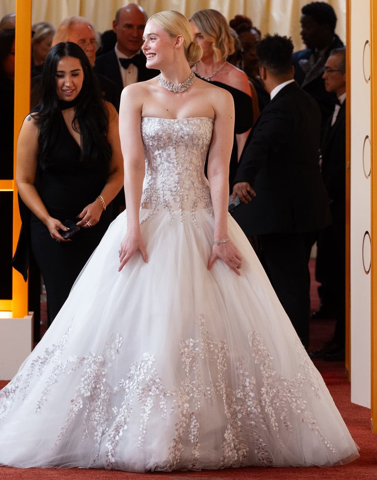 Elle Fanning glows in a strapless custom Givenchy gown adorned with delicate wisteria embroidery, paired with a diamond choker and soft tulle skirt at the 2026 Oscars