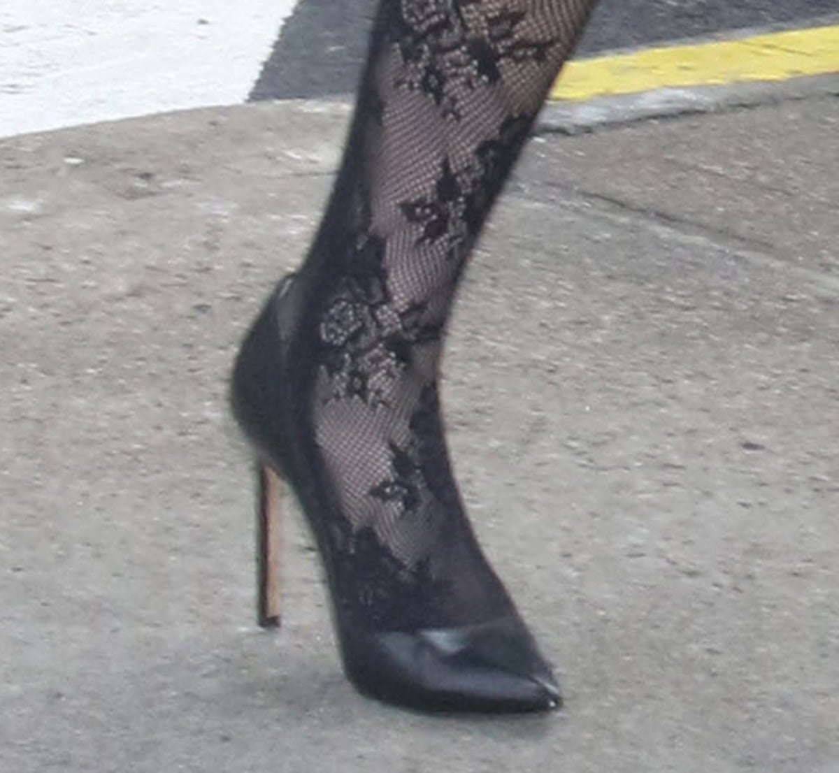 Emma Chamberlain keeps it simple with classic black pointed-toe pumps and floral-embroidered fishnet stockings